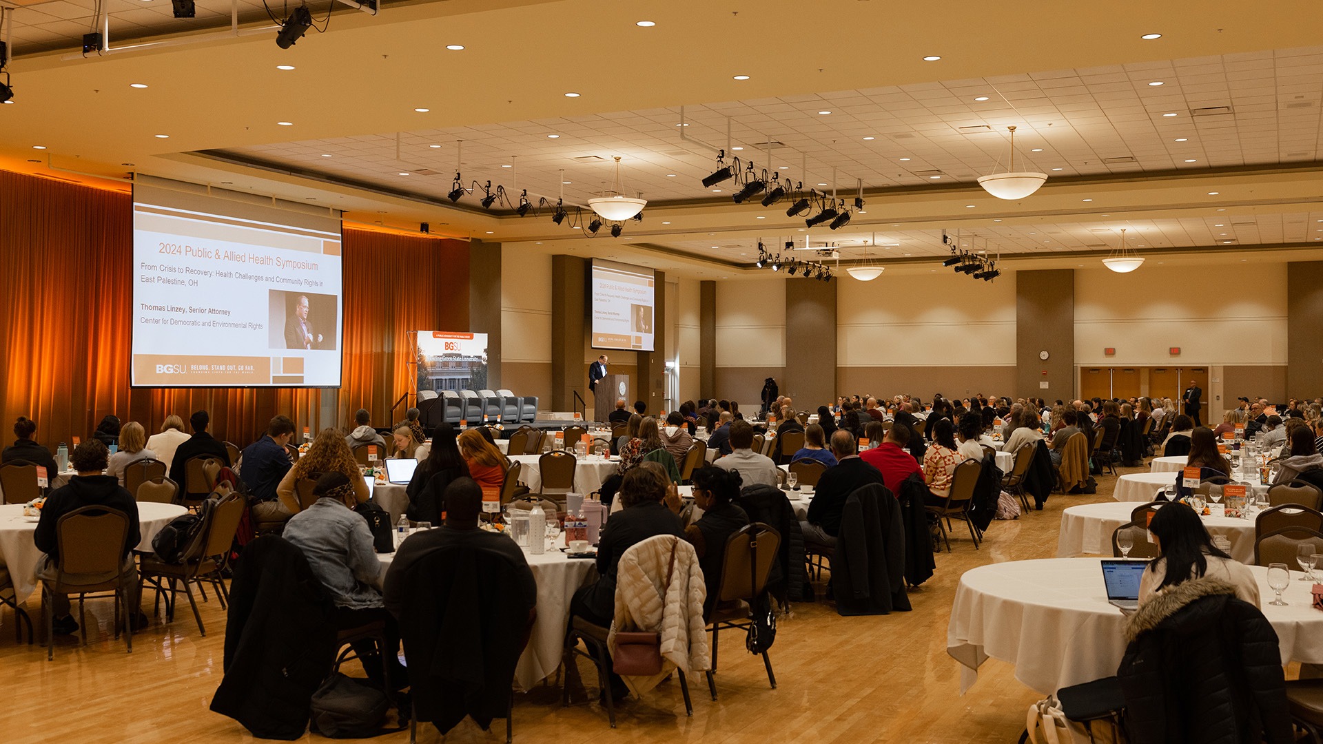 People sit at round tables in a large ballroom