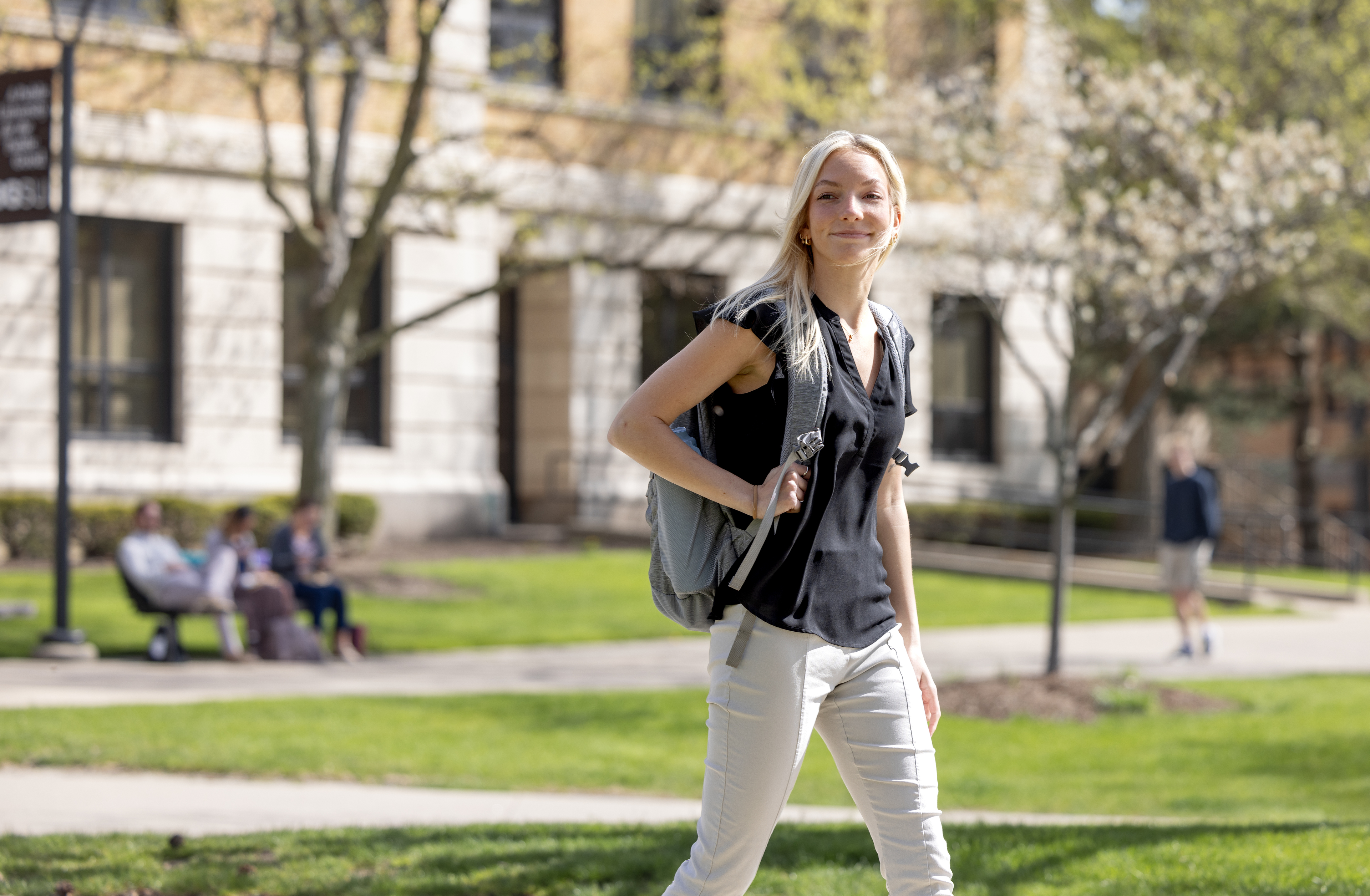 A girl walks through campus with a backpack.