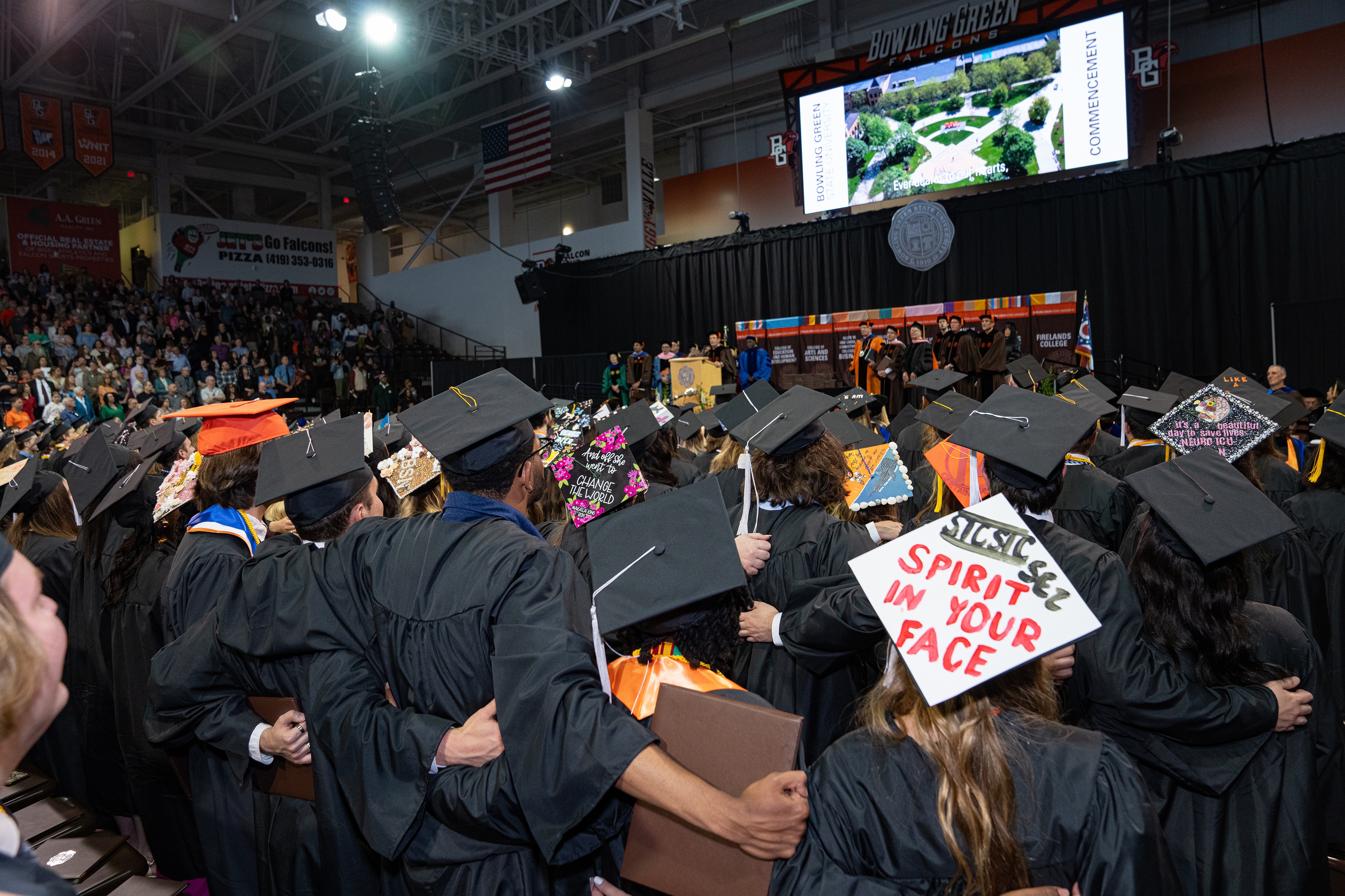 Graduates stand up and sing together