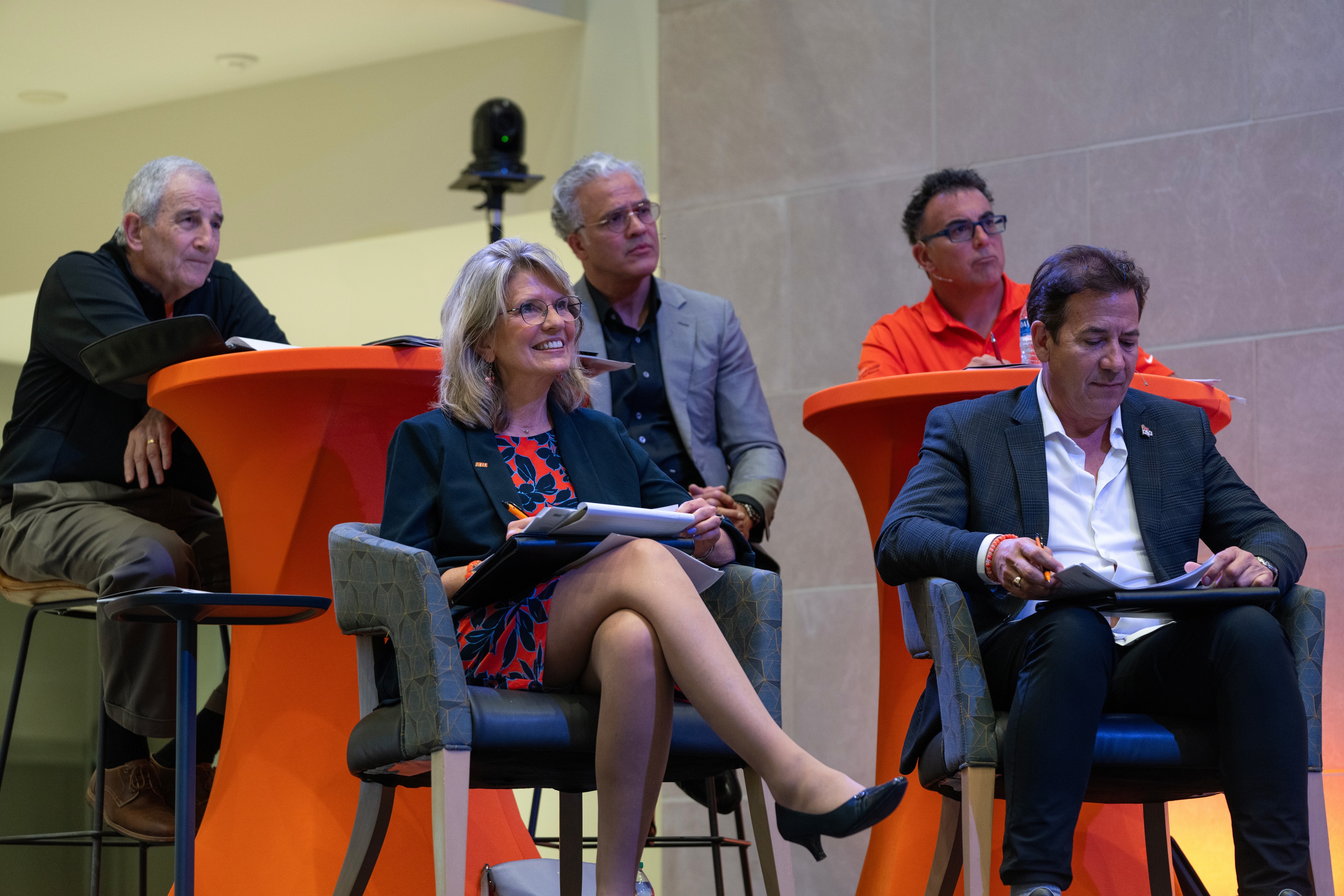 A panel of five judges sits in chairs on a stage