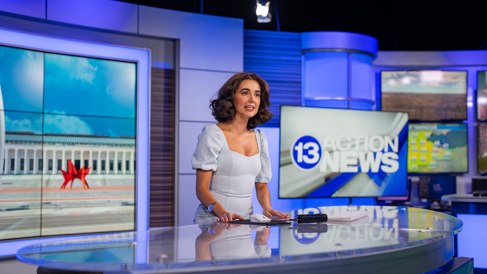 A person sitting behind an anchor desk reporting the news.