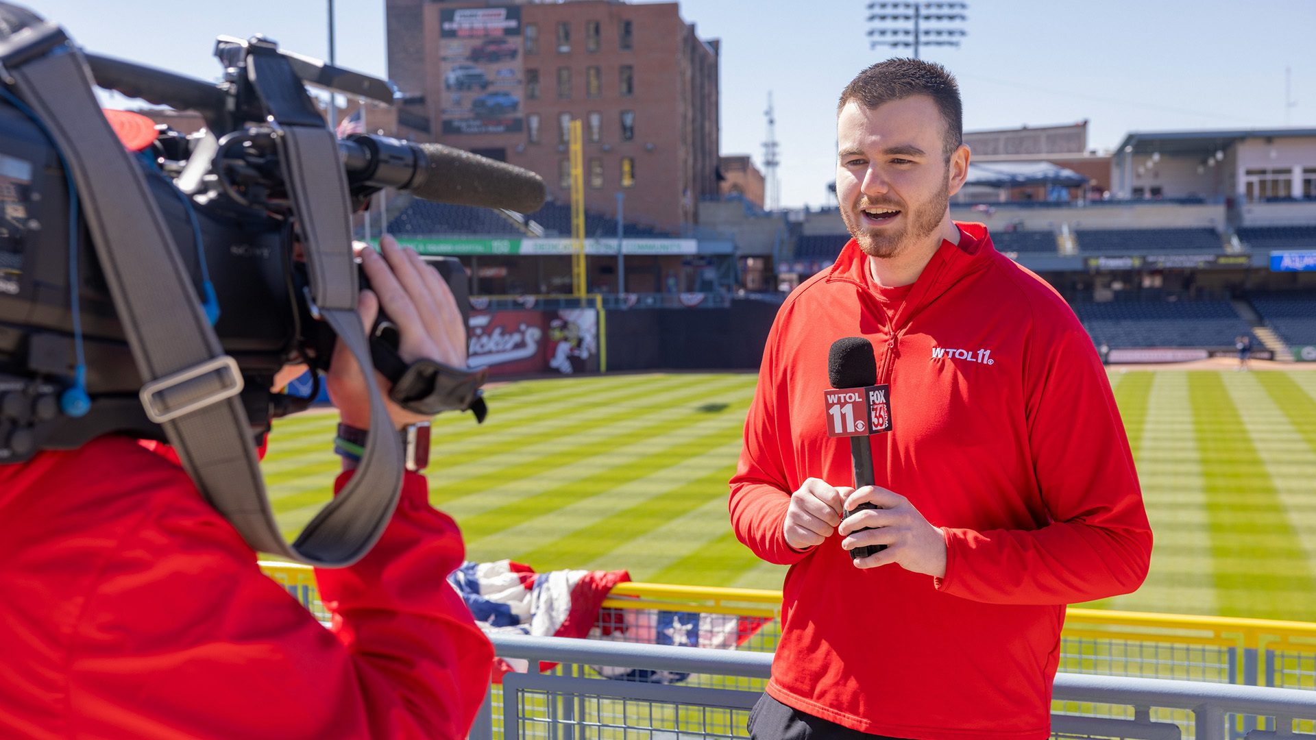 A person holds a microphone while being recorded for a TV news broadcast.