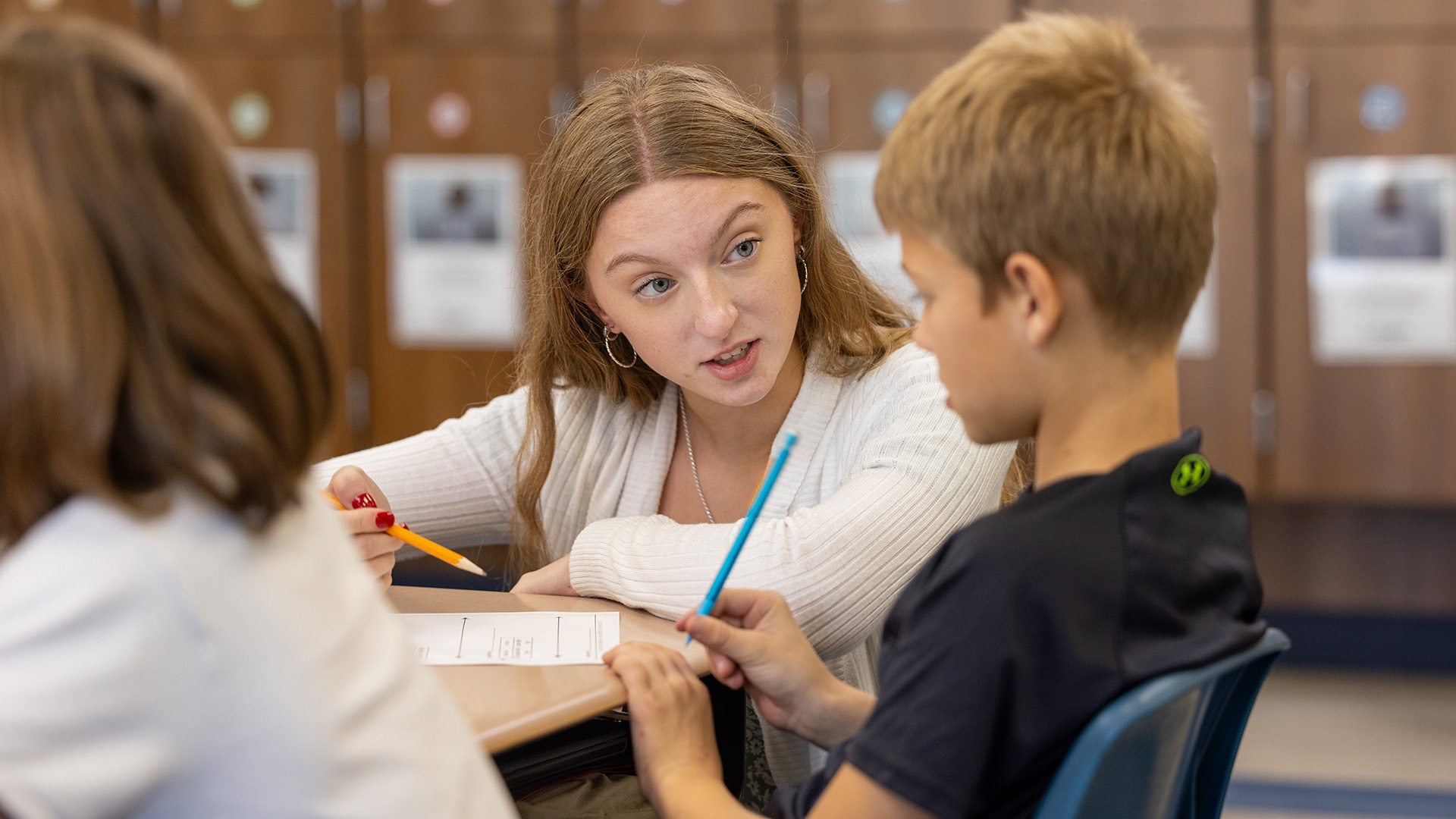 A person helps a child with an assignment.