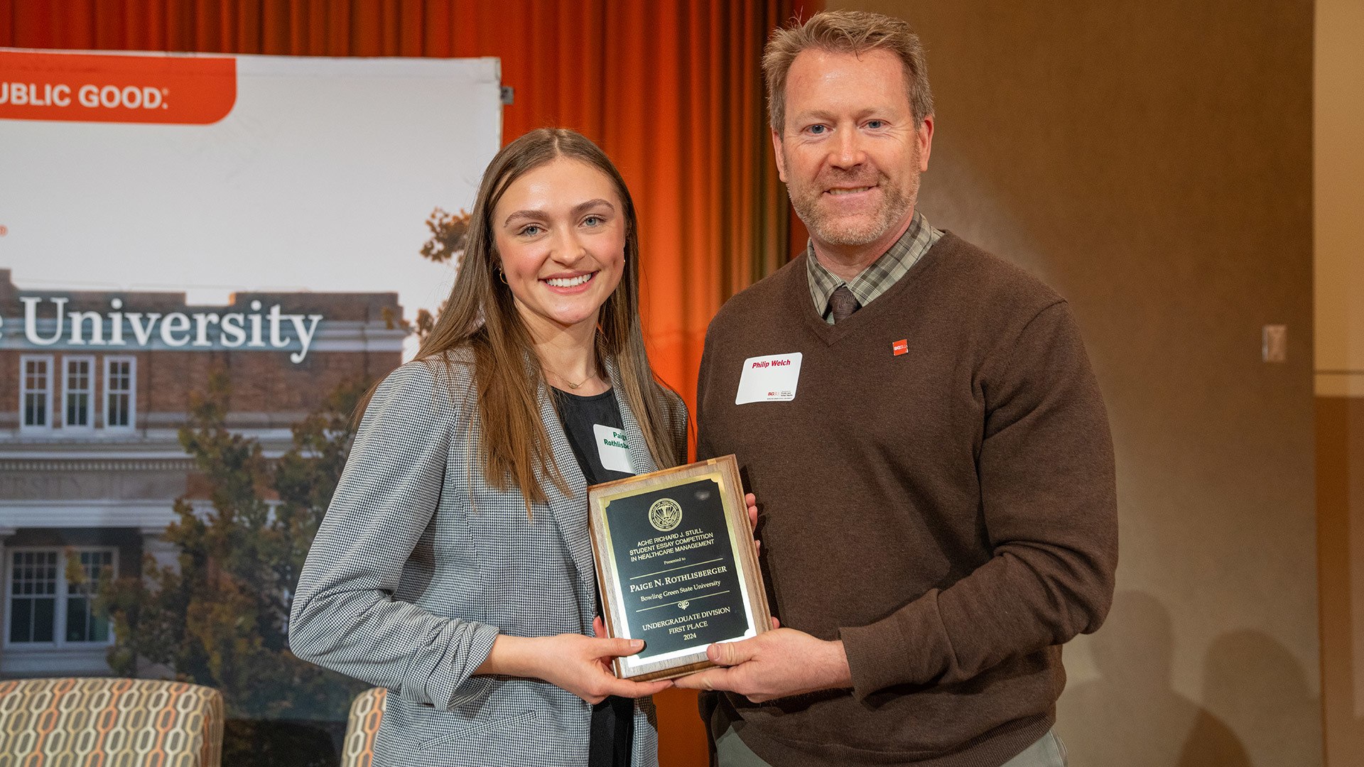 A woman holds a plaque for winning an award.