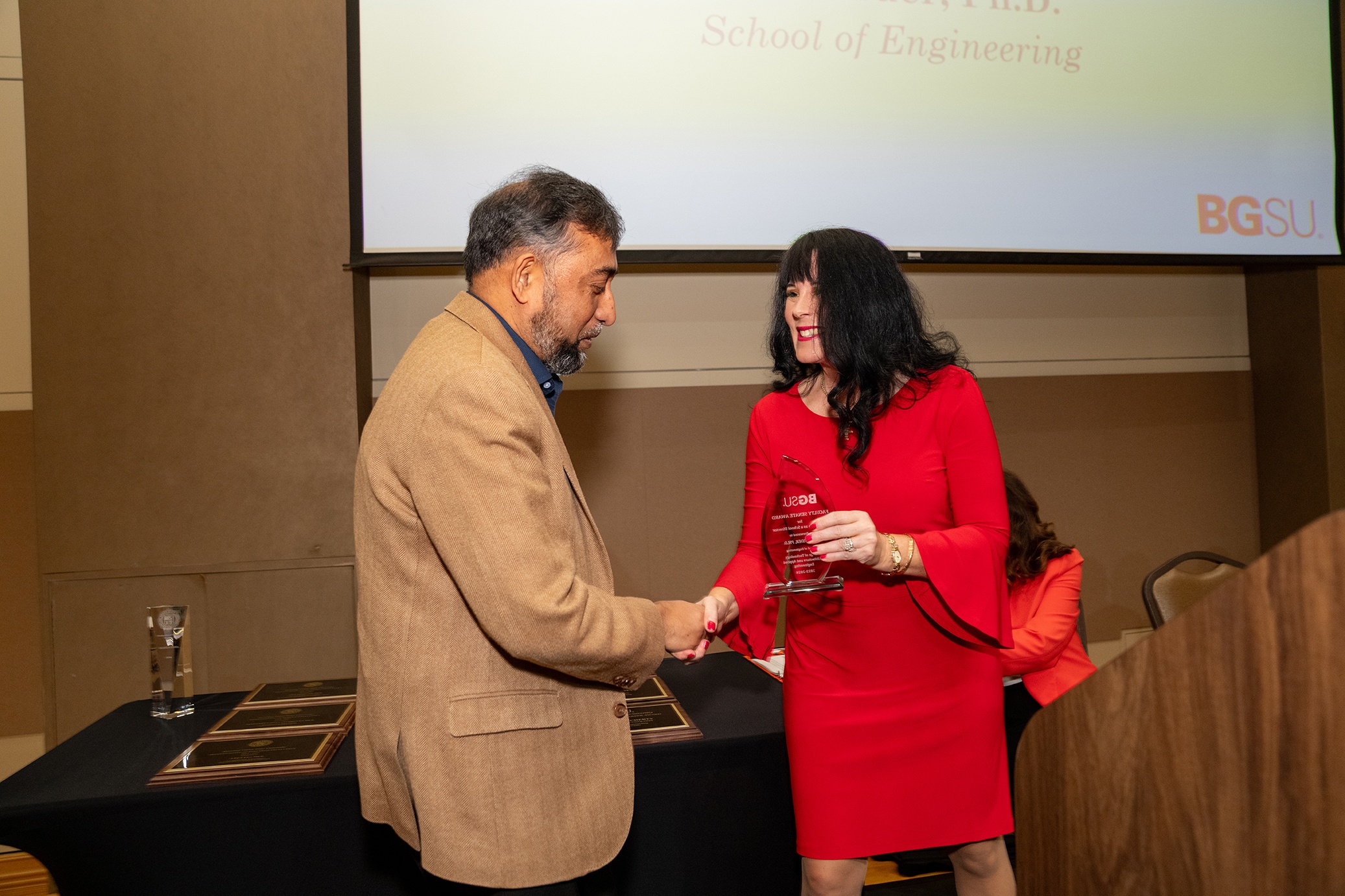 A man receives a glass trophy from a woman 