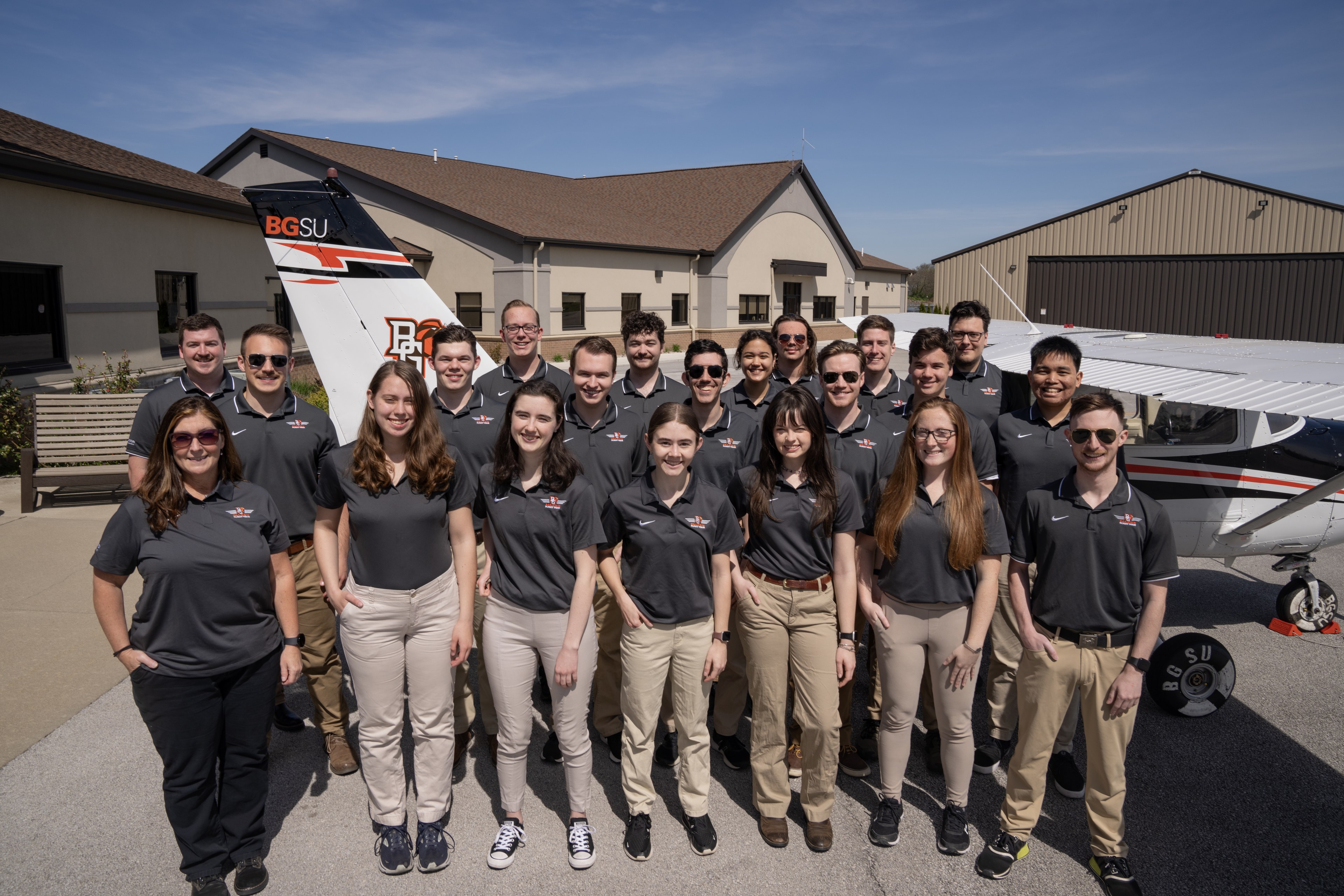 A group of BGSU students stand in front of an airplane.