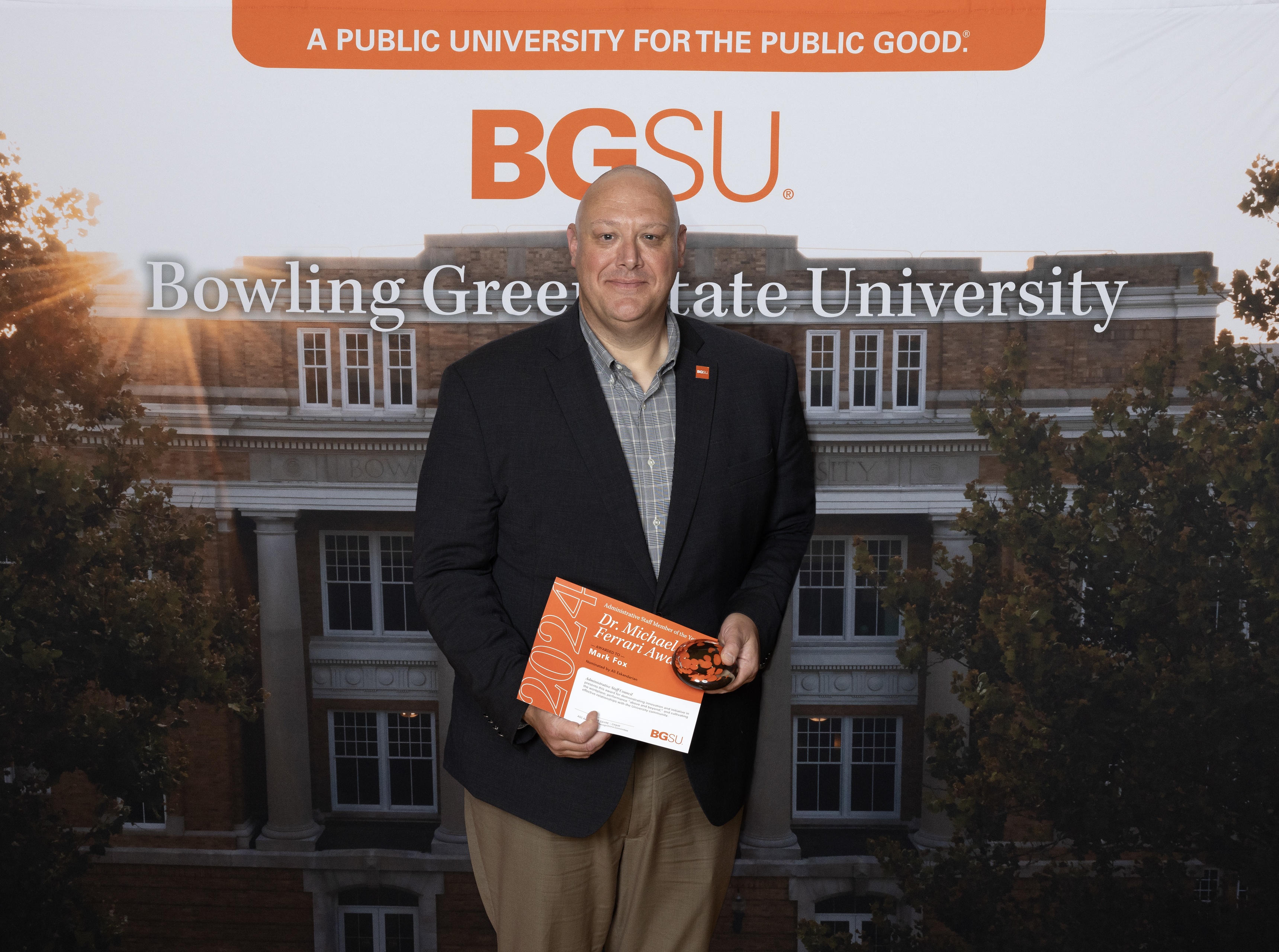 A man holds an orange award certificate 