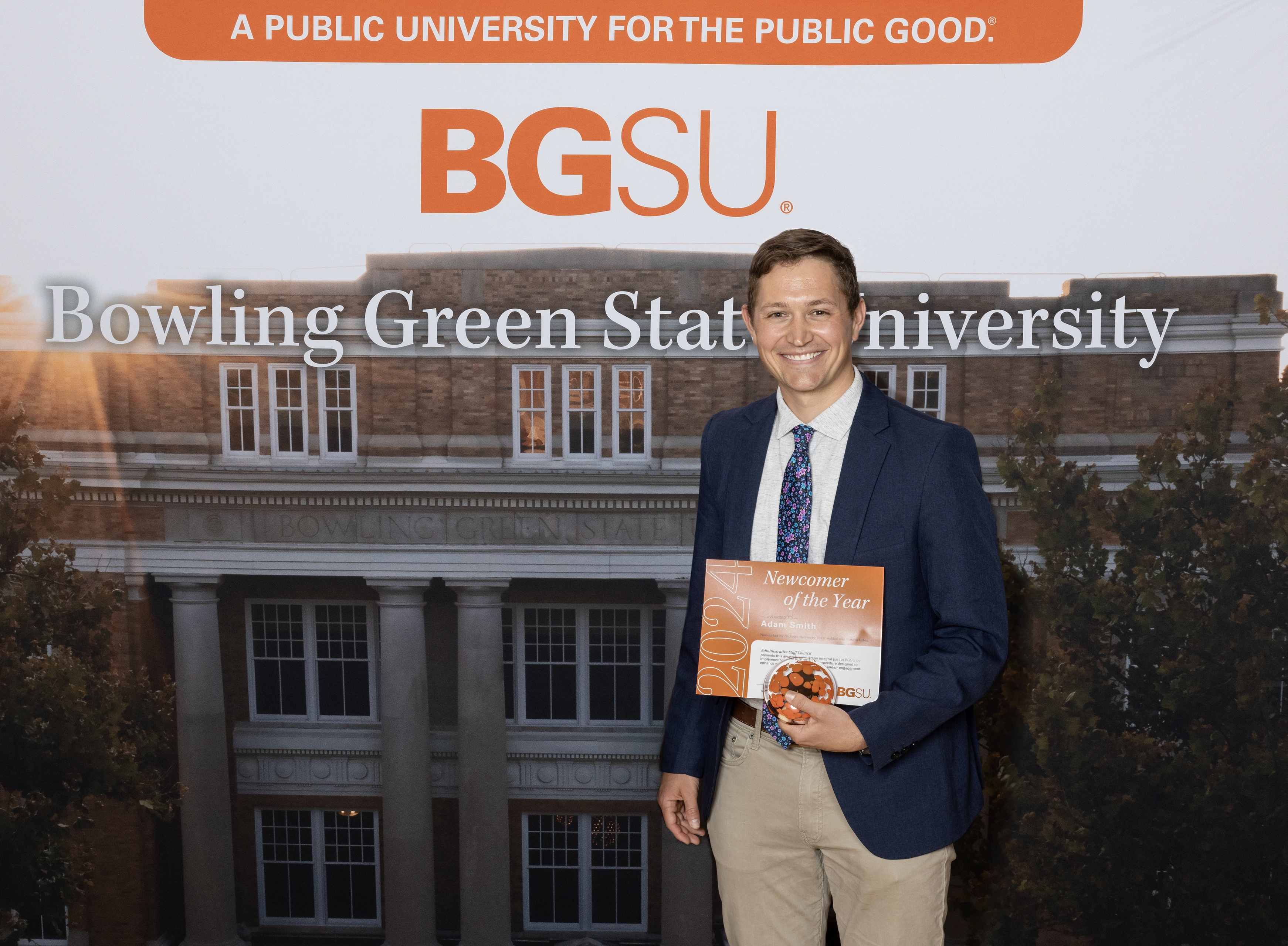 A man holds an orange award certificate 