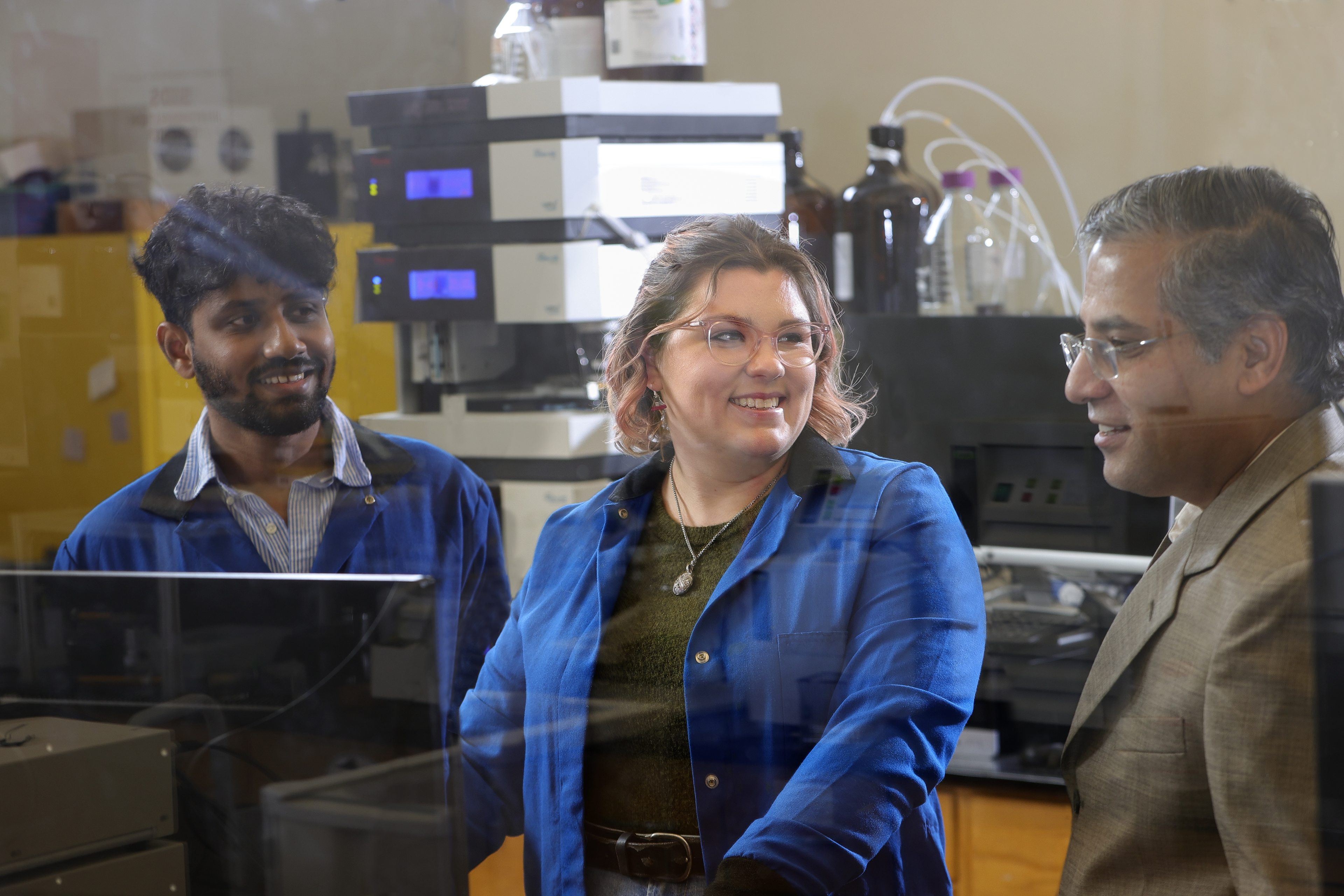 Two students with professor in photochemistry lab