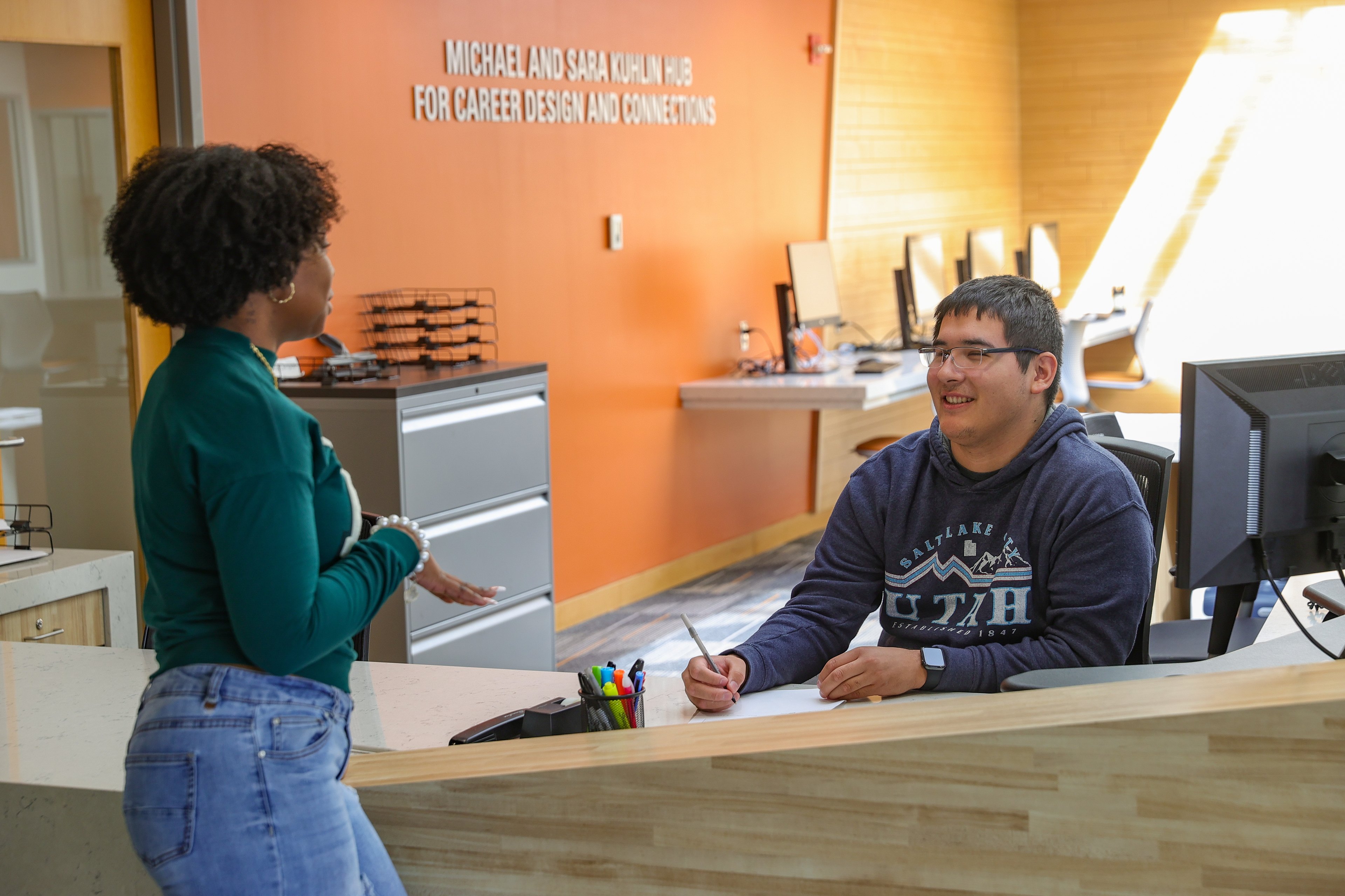 Two people talking at a desk