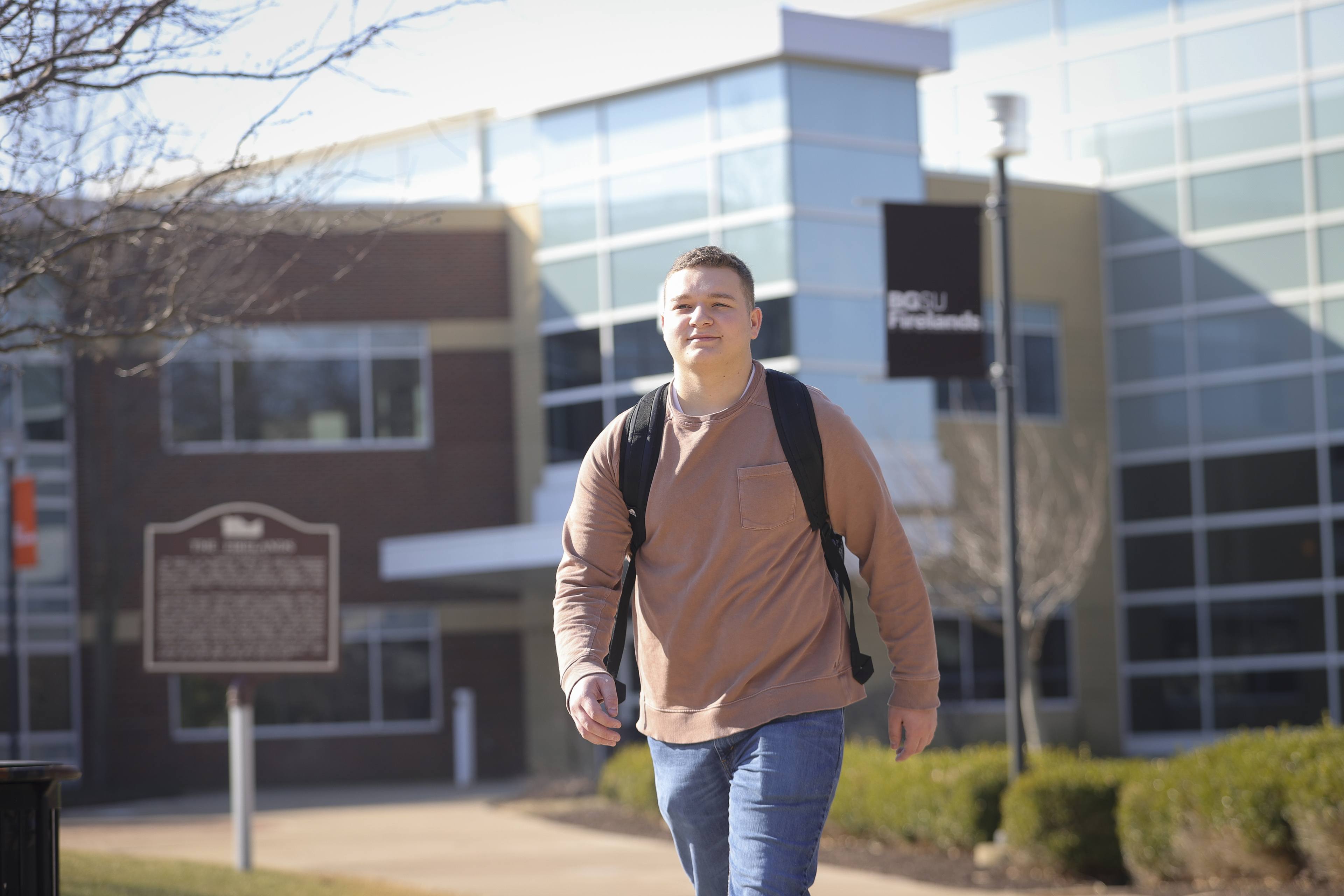 student walking across BGSU Firelands with bookbag.