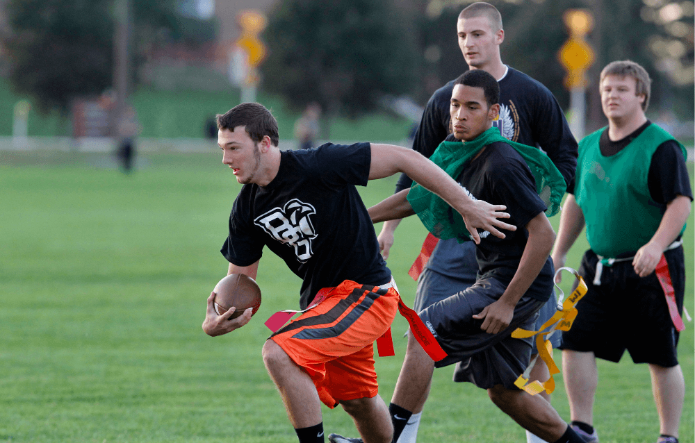 Four students playing flag football