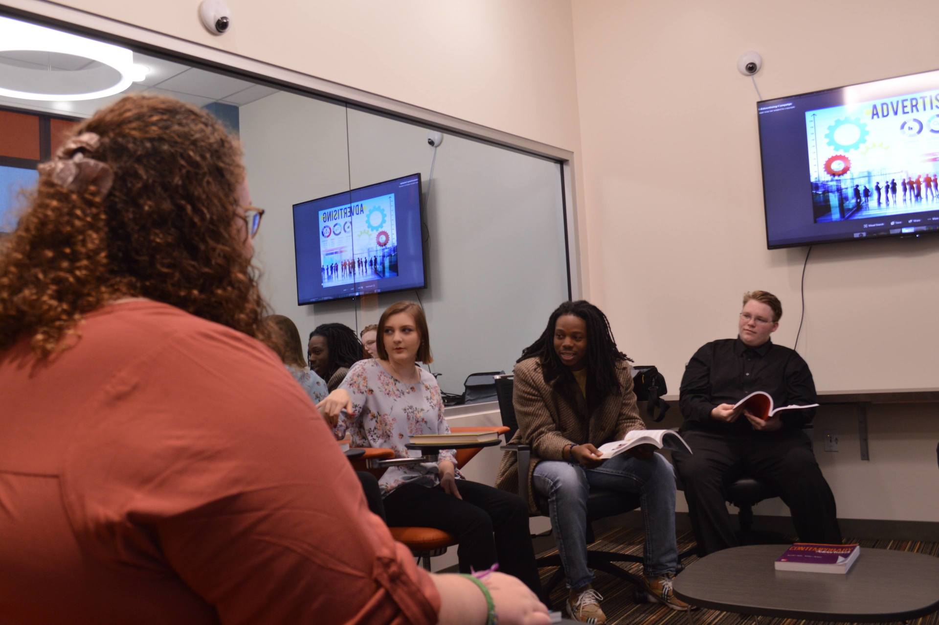 BGSU Advertising major students hold a class in an Ohio classroom with a two-way mirror for conducting focus groups for audience research.