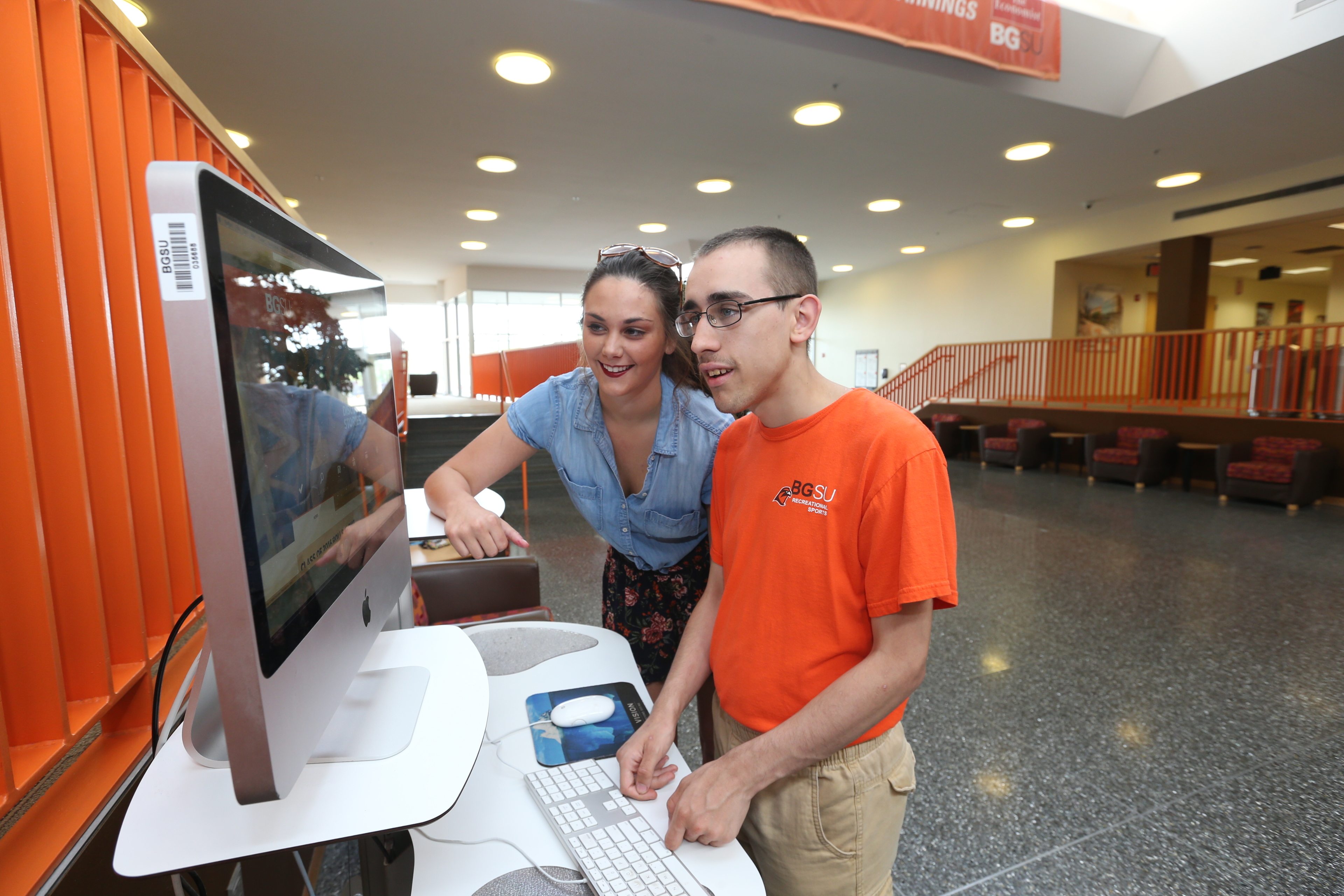 A female student in the BGSU master’s program in special education with a specialization in autism spectrum disorders works on a computer with a young man with autism.