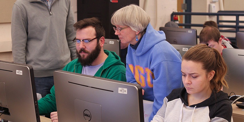 Software engineering professor assists students at a computer