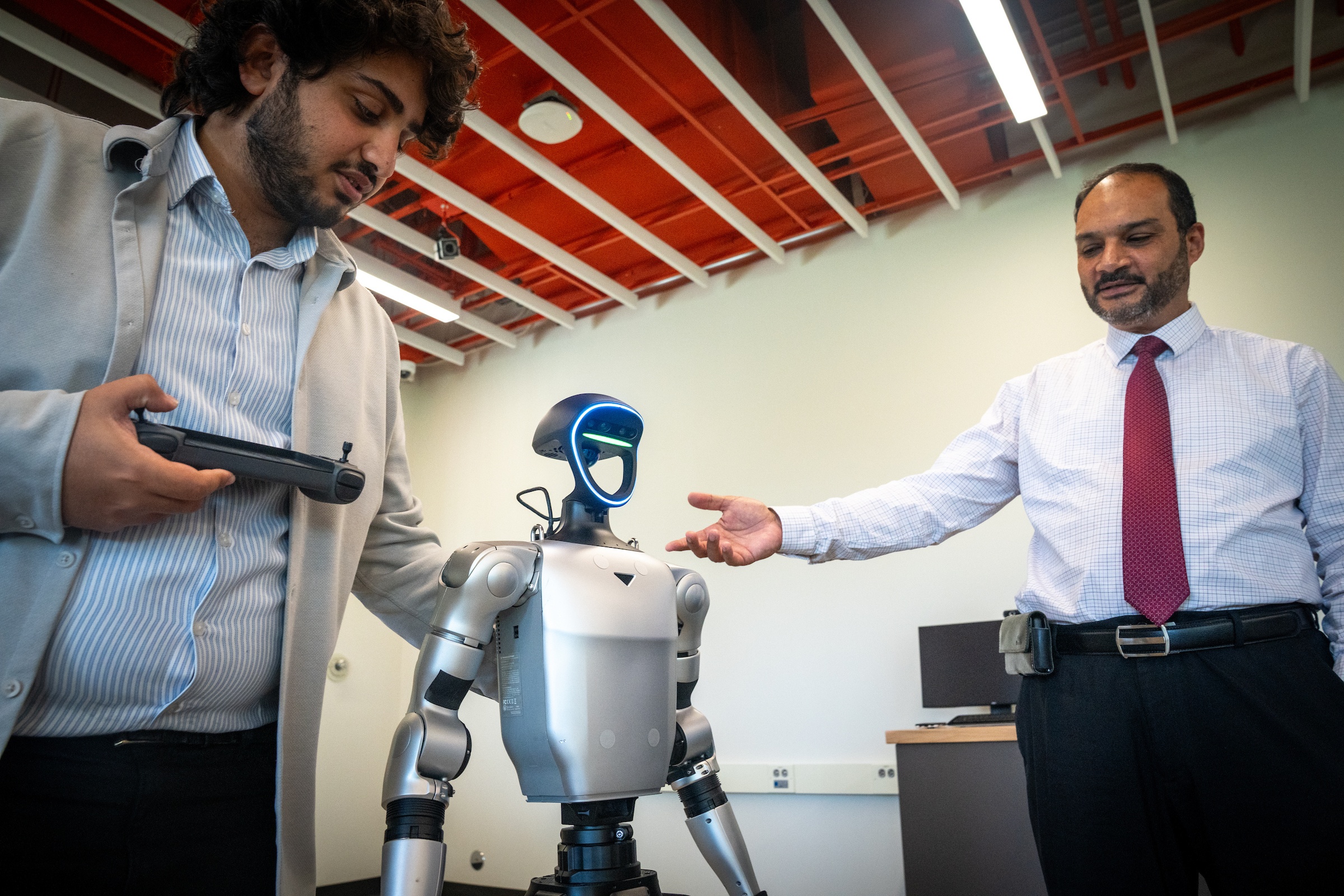 Two people stand next to a robot.