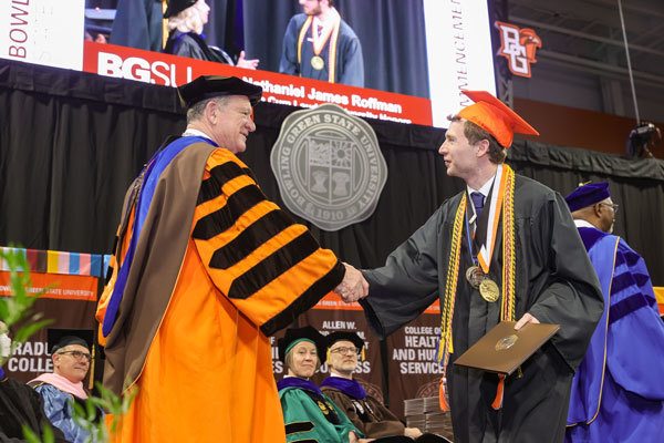President Rodney Rogers shaking hands with Matt DeAmon at the 2023 Commencment Ceremony in the Stroh Center on BGSU's campus.