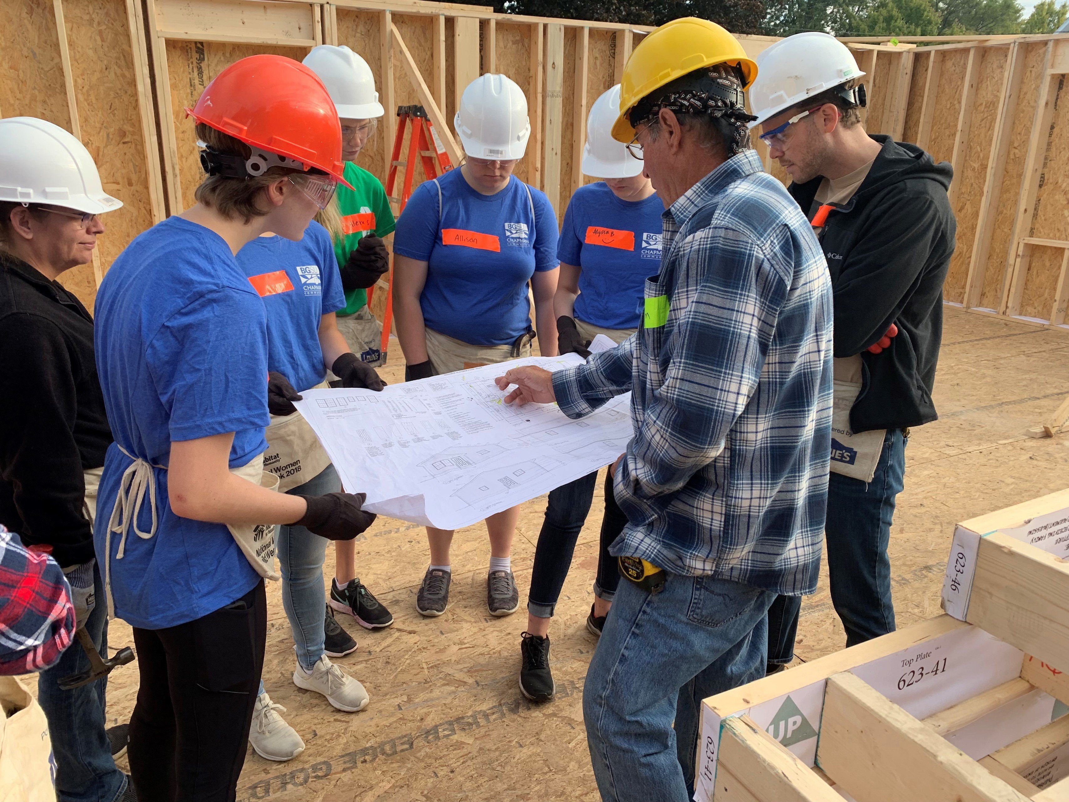Students from Chapman Learning community look at house blueprints with a contractor during the Habitat for Humanity house build in 2019