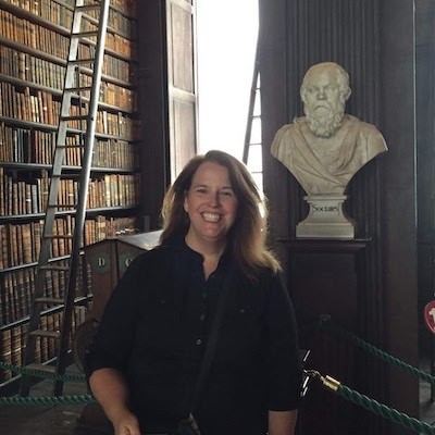 image of Sarah Caserta standing by a statue and bookshelves