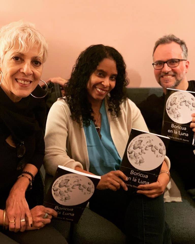 Three people holding copies of the book