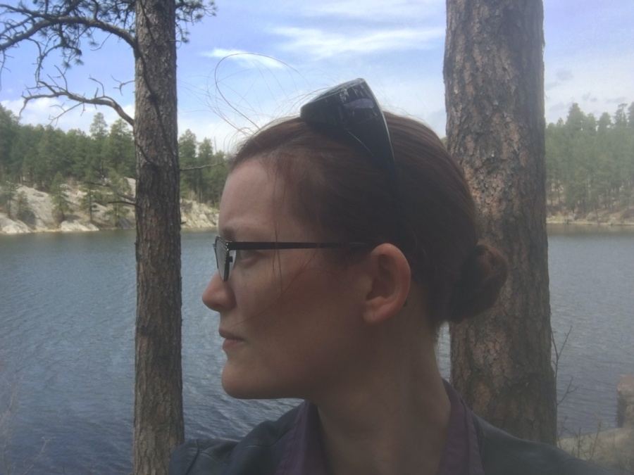 Photo of Charity Givens looking to the side in front of a lake and treeline