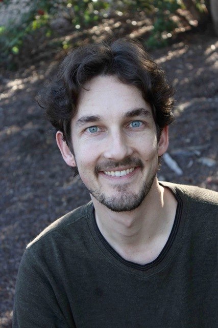 Professional image of Dr. Ryan Ebright. He is smiling at the camera while outside in a wooded area.