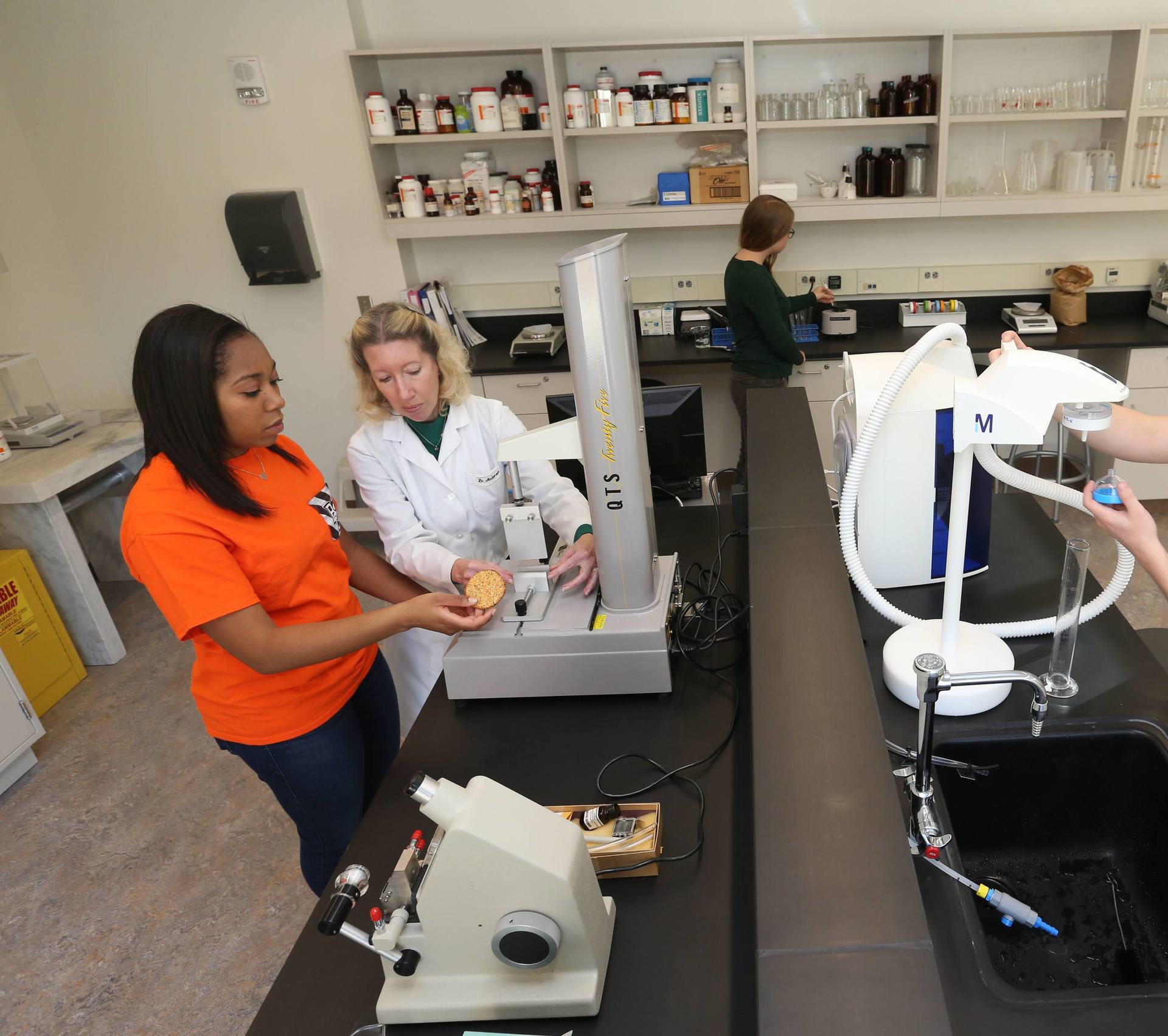 Three BGSU students in an on-campus food science lab examine a solution with a professor. Study Food and nutrition online, or on campus.