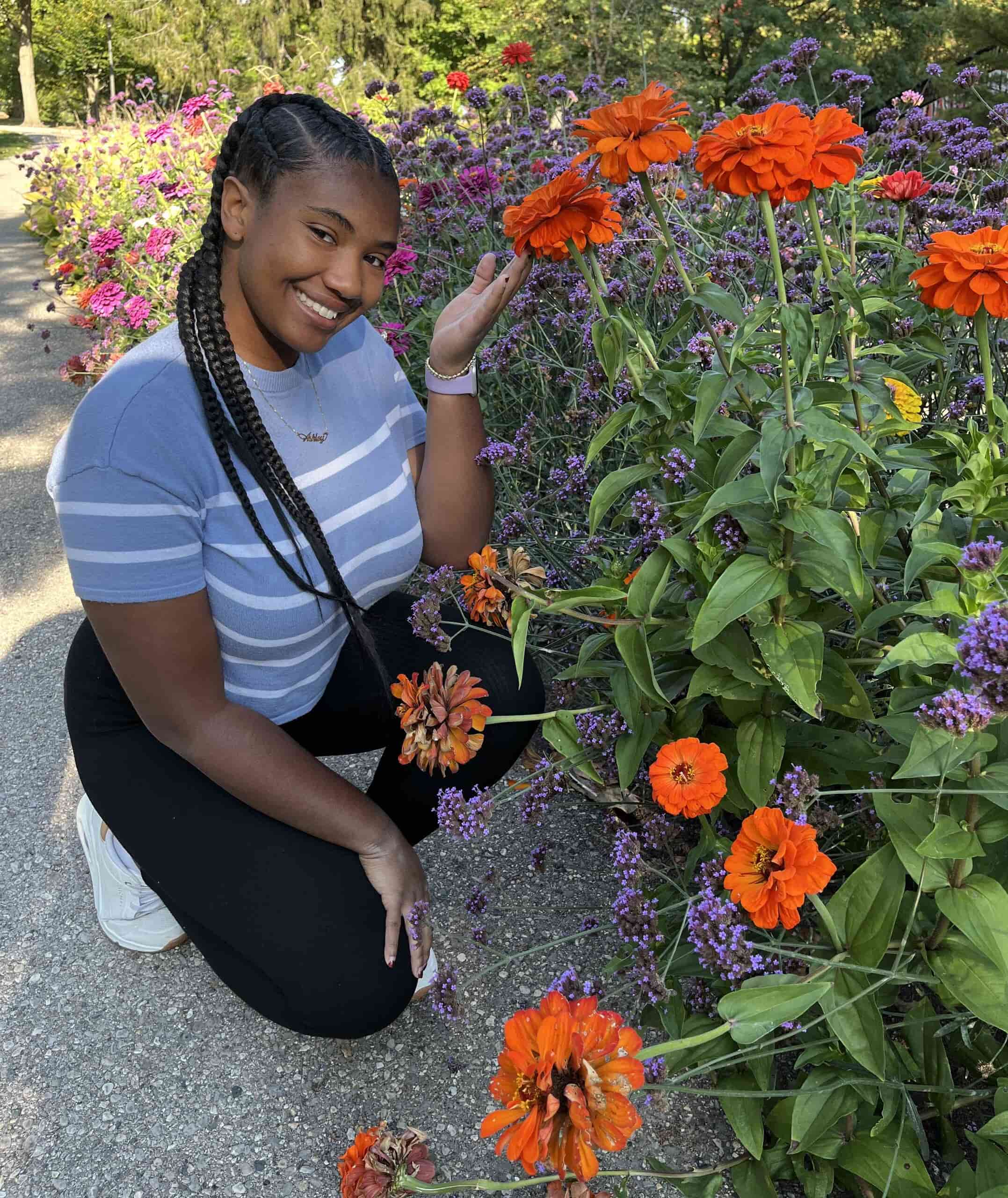 Ashley Rodgers outside kneeling near organge flowers in a garden