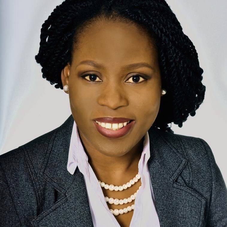 Professional headshot of TJ Doro wearing a grey suit