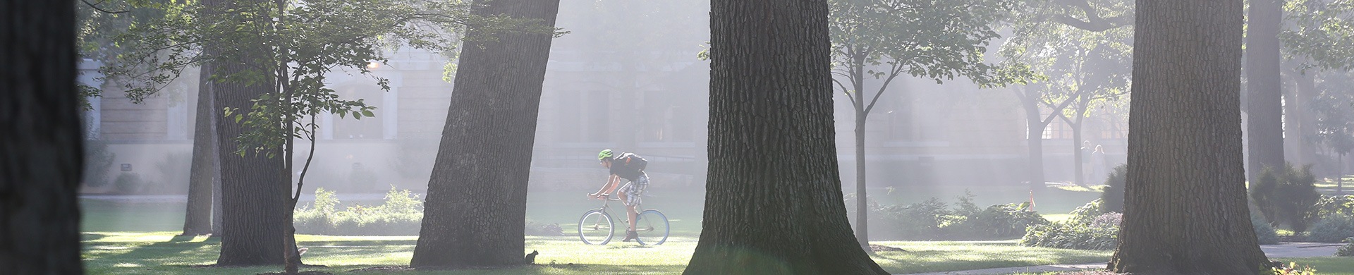 Person riding a bike across old campus