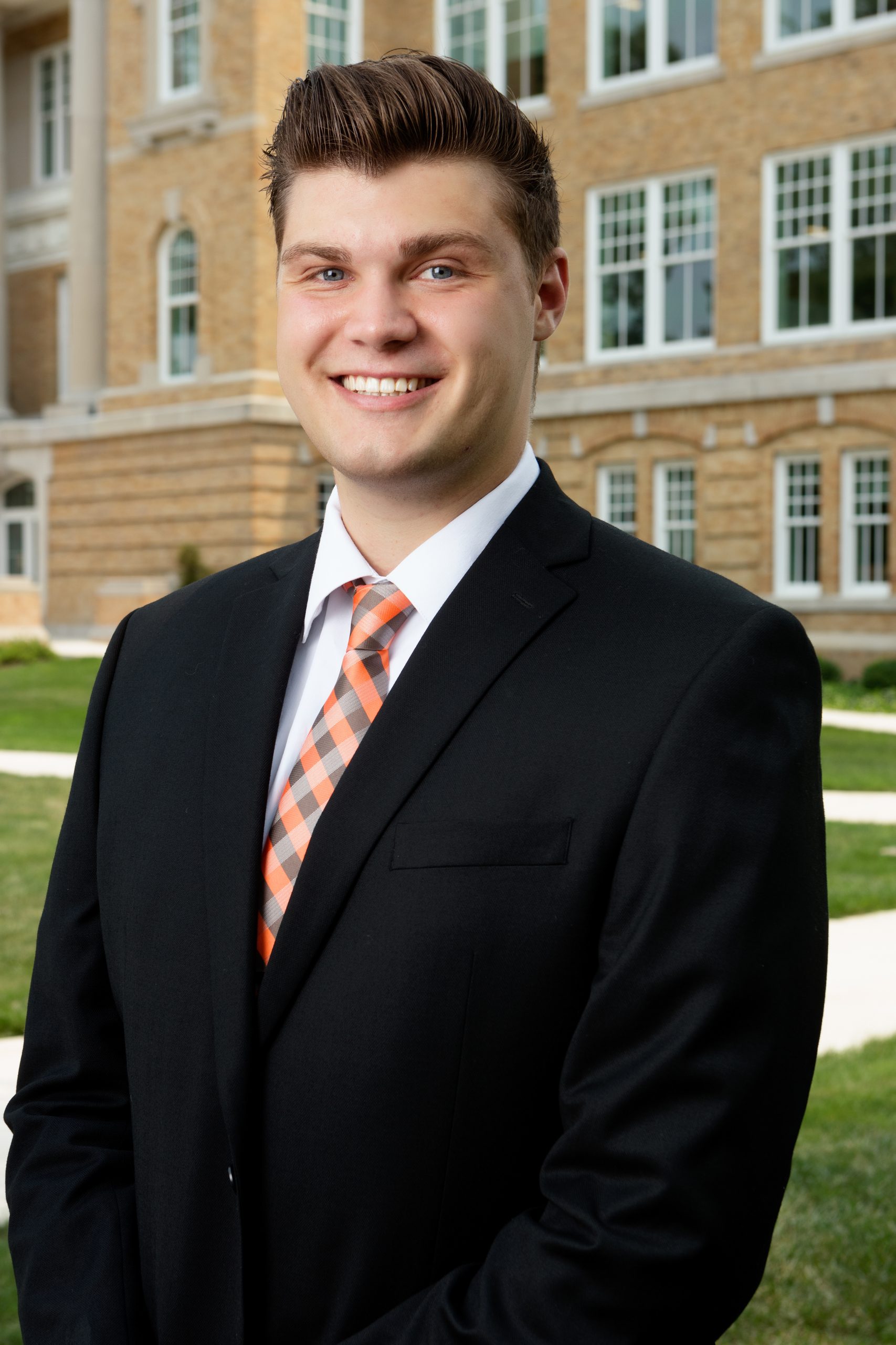 Nick Malendowski, wearing formal attire, standing in front of University Hall at Bowling Green State University
