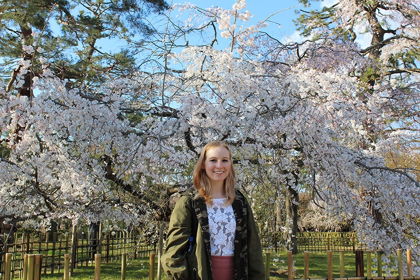 Nautica Savage standing in front of cherry blossom trees