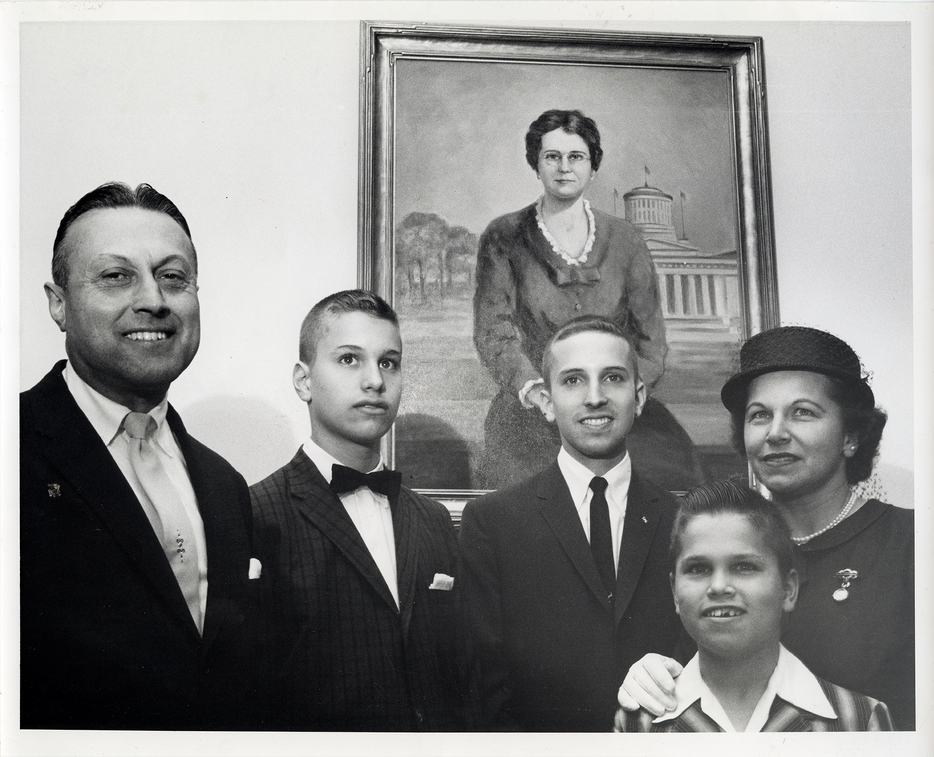 Martin Hanna, son of Myrna Reese Hanna, stands with his family in front of her portrait in June 1960.