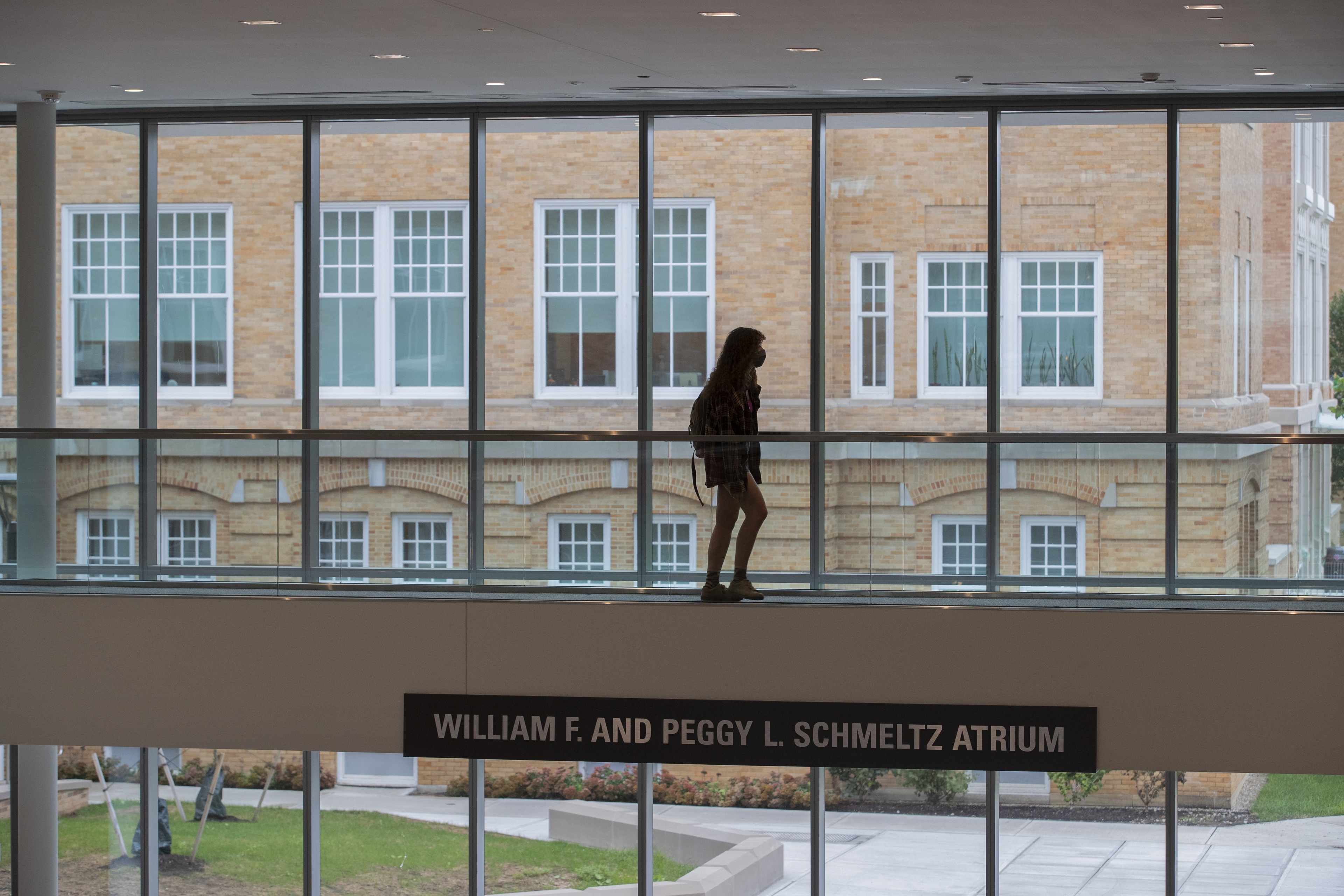 A student is silhouetted by University Hall as she walks through the Maurer Center.