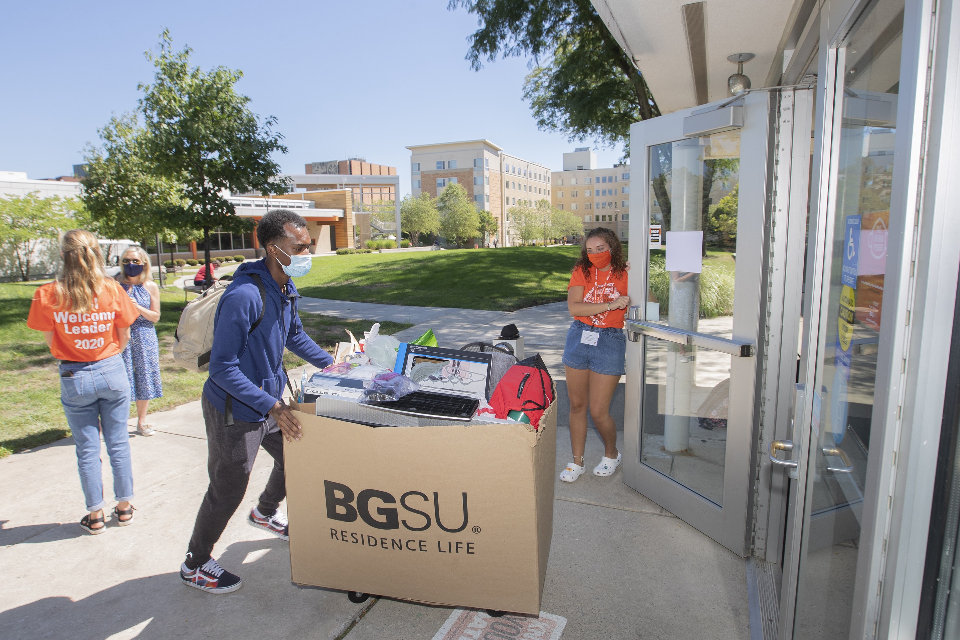 A BGSU welcome leader holds the door for a student moving into a residence hall in August. Students moved in over the course of several days before the start of the fall semester. 