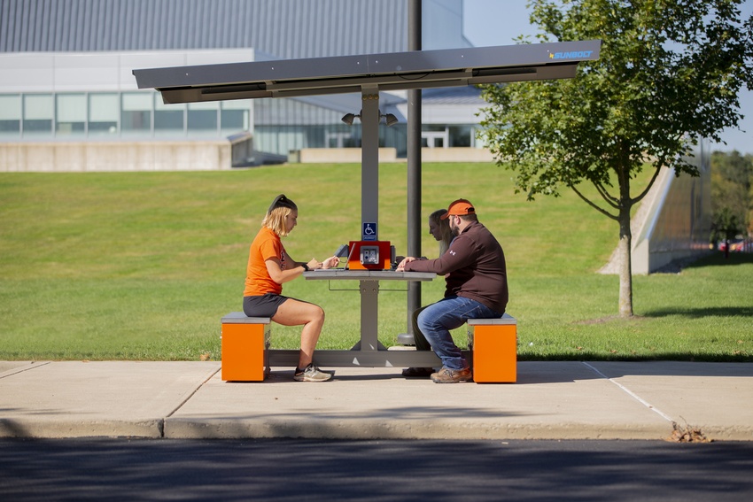 Students sitting at charging table on campus
