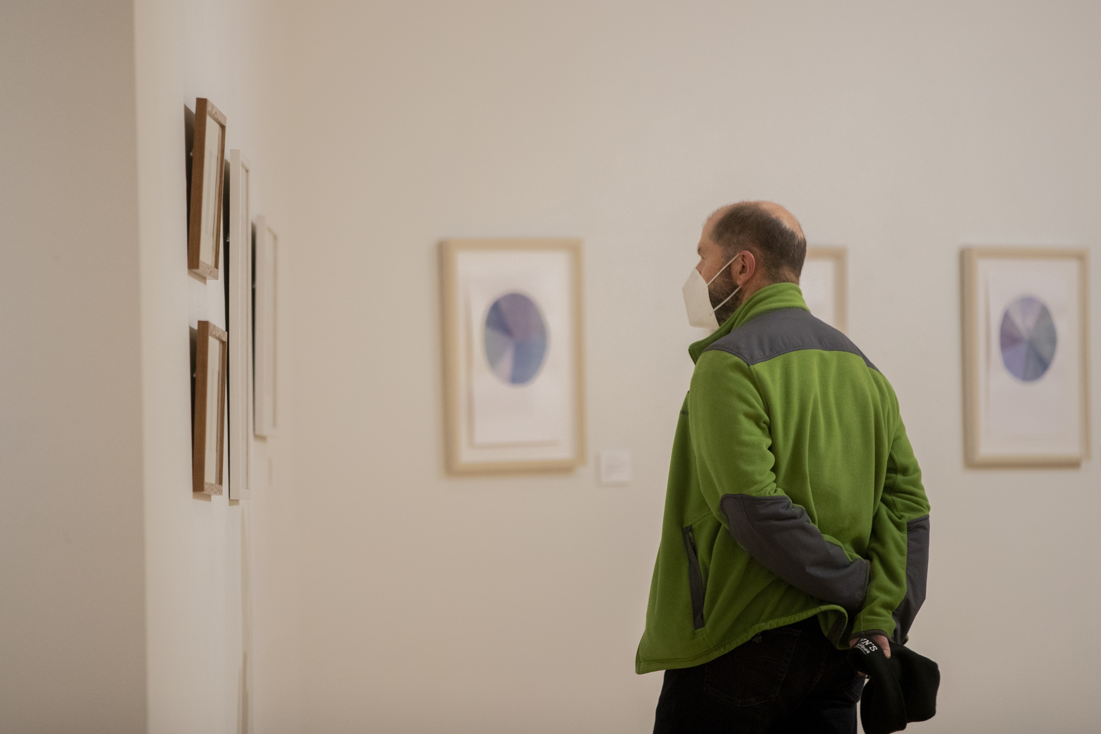 An individual looking at art hanging on the wall in a gallery