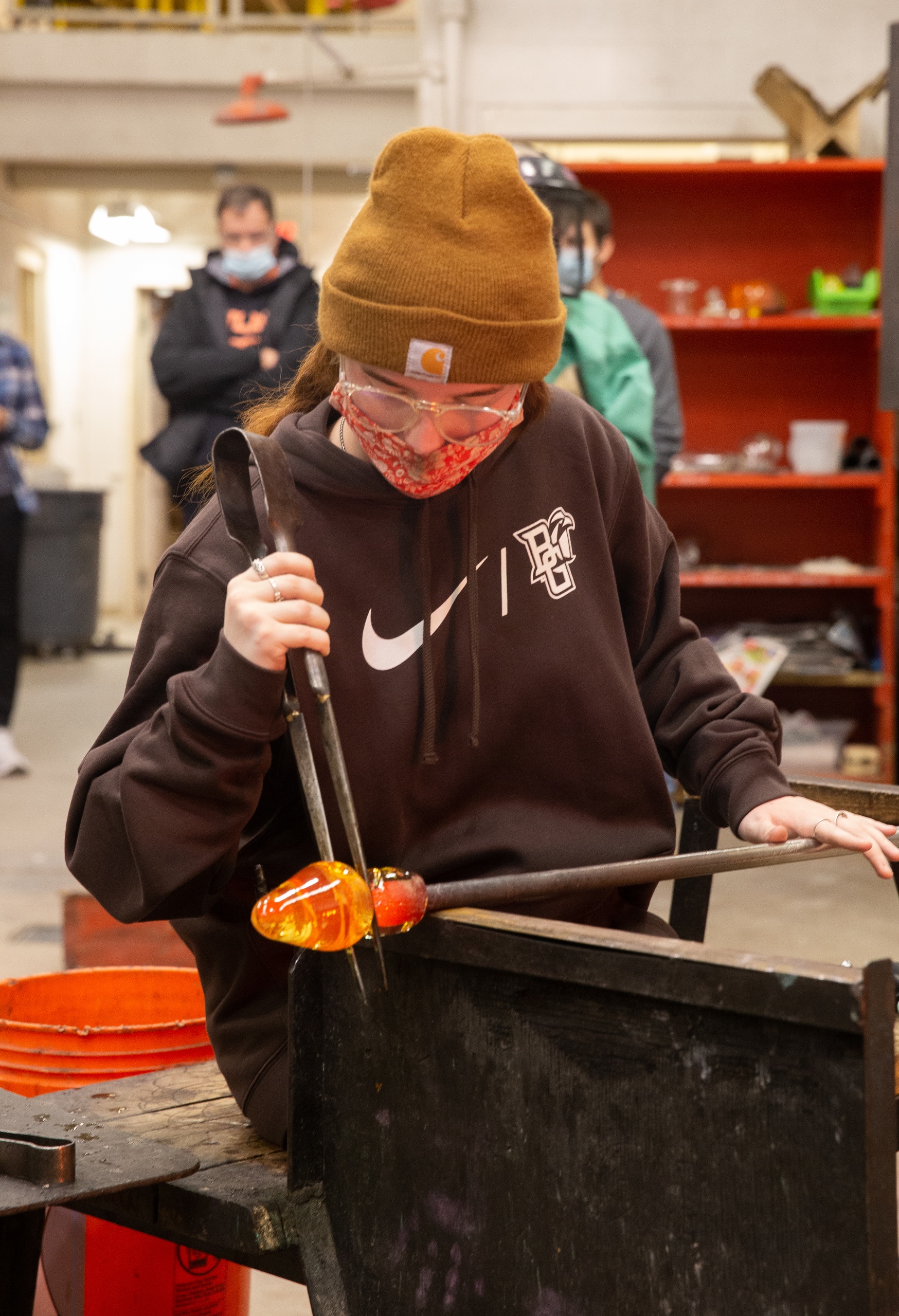 Student demonstrates glass blowing techniques while spinning a piece of glass