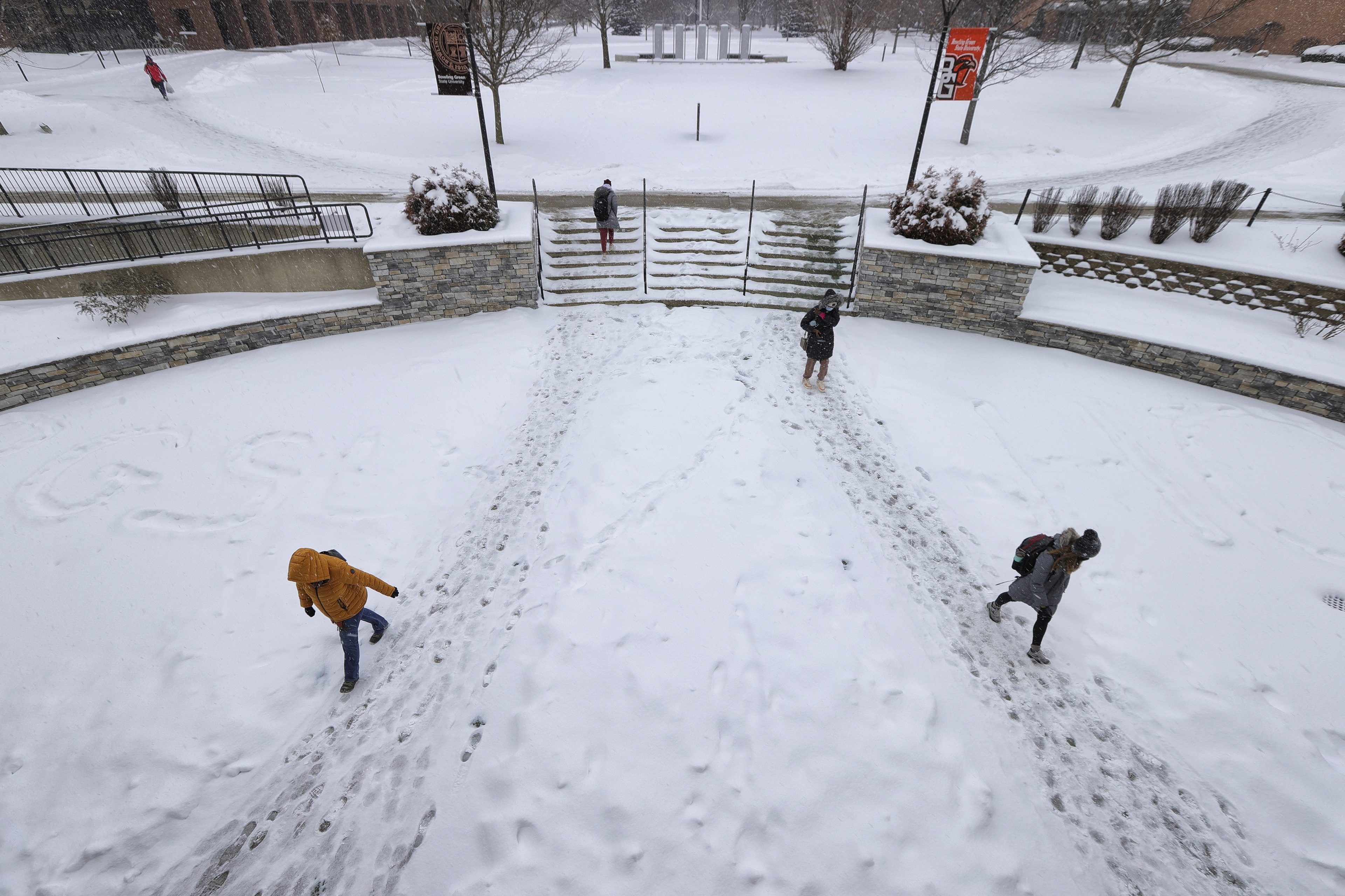 Students enter and exit the Jerome Library, leaving footprints in the snow. 