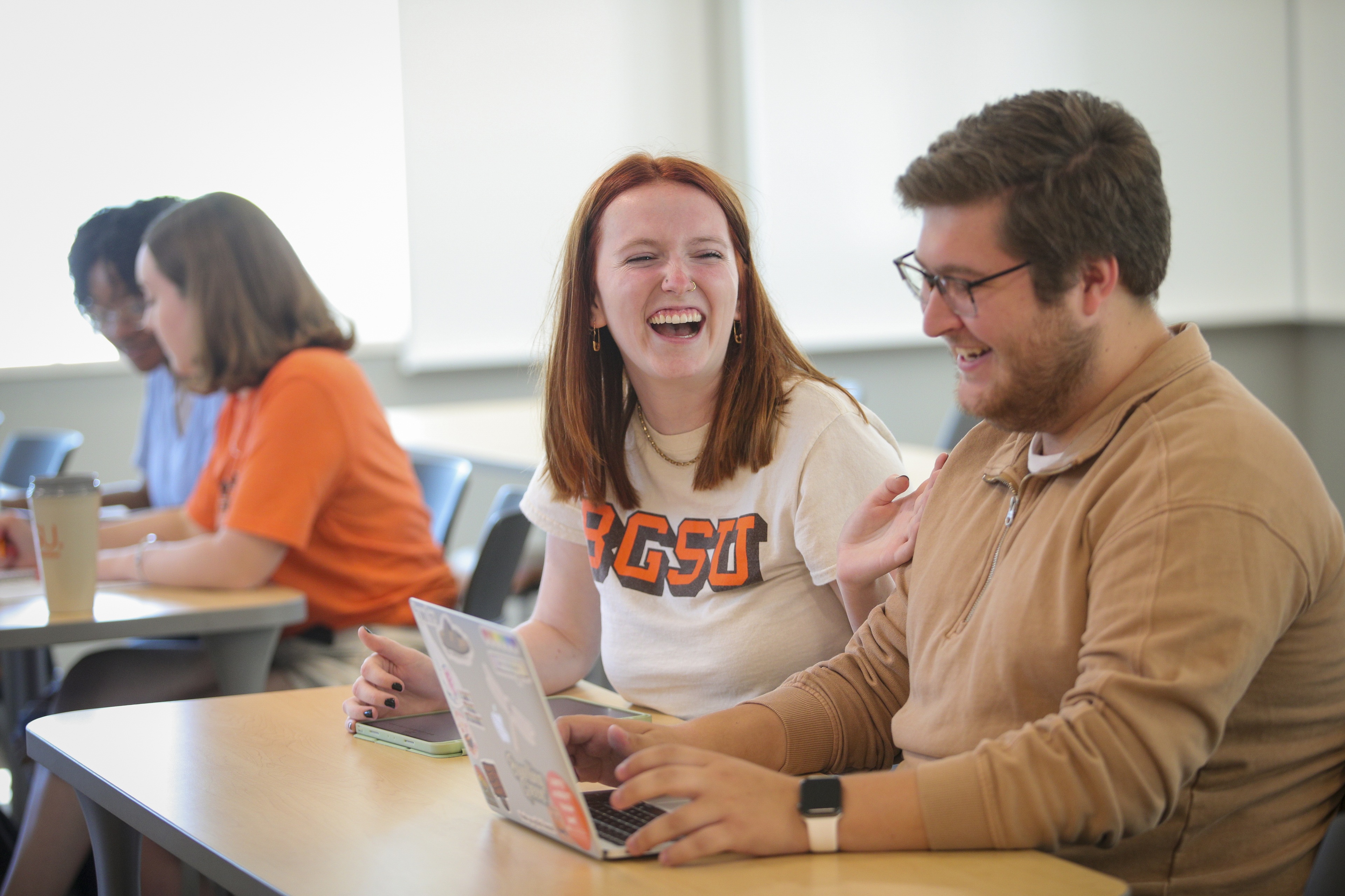 Students laugh as they work together in a sunny classroom at BGSU. 