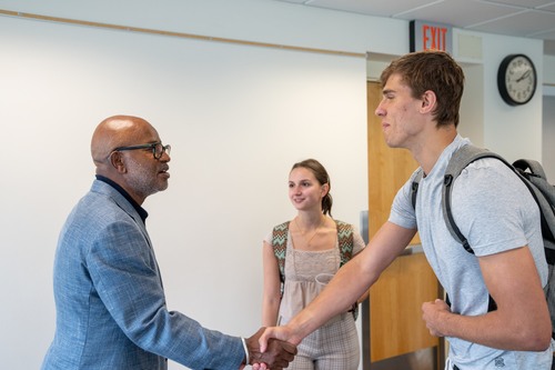 Charles Albert Daniels Jr. shakes a student's hand