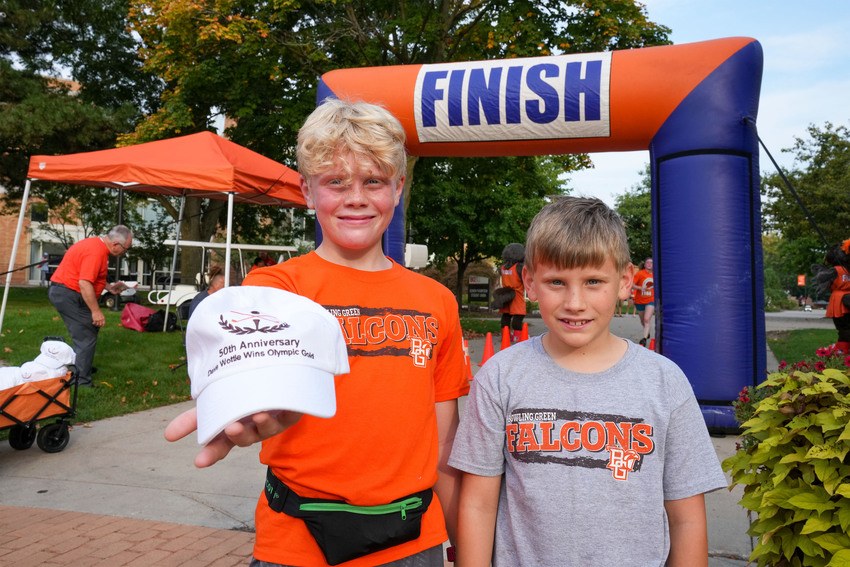 Two kids show off the Dave Wottle commemorative race cap that was given away during homecoming, marking the 50th anniversary of the gold medal 800m run by the BGSU alumnus.