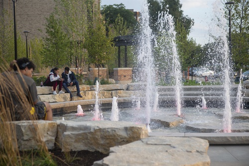 Students sit at the Schmeltz Family Fountain at the Alumni Gateway