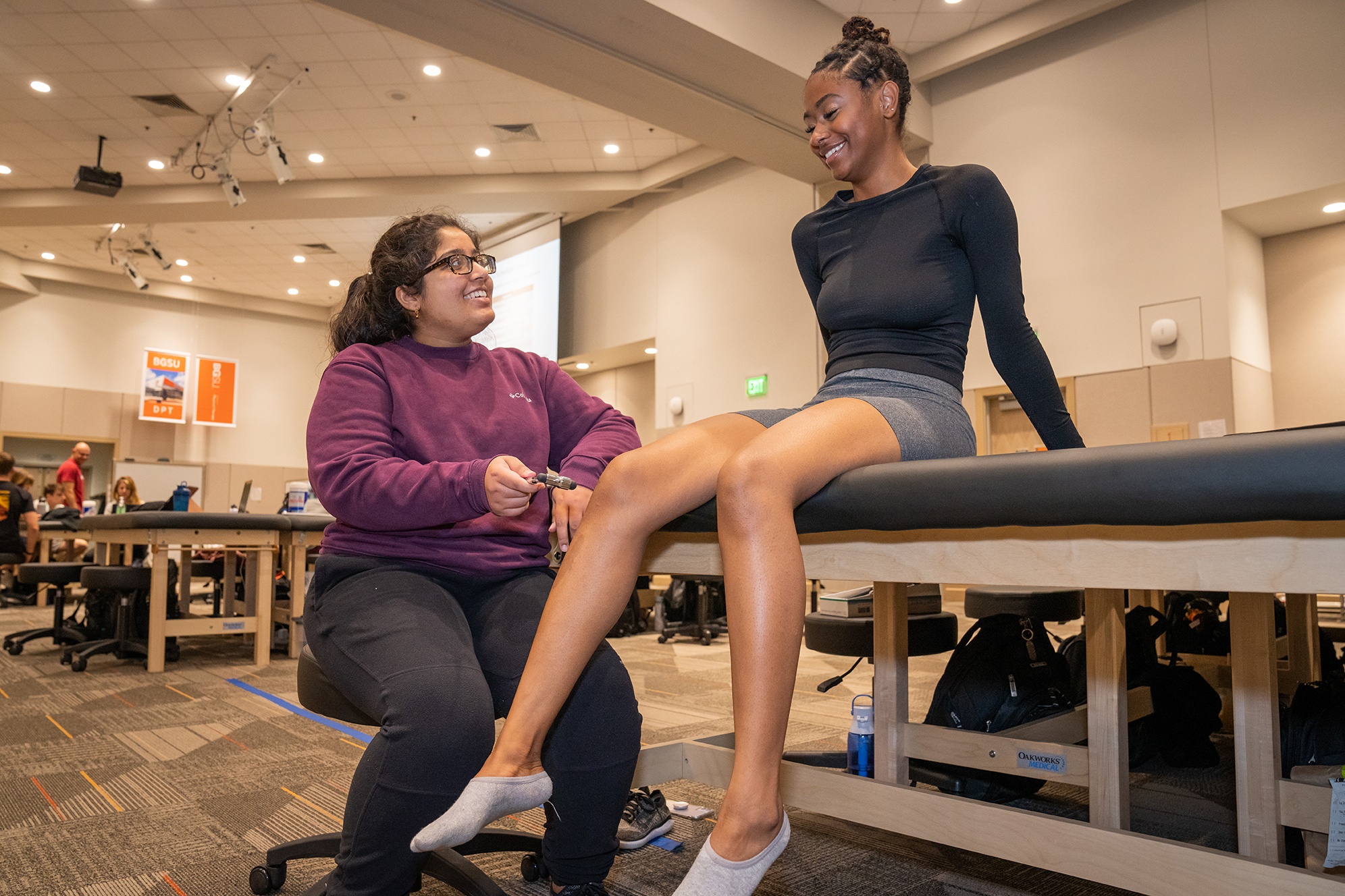 Meena Dhawan checks the knee reflexes of her classmate Mekayla Abrahams during a recent two-week visit to campus as part of the University's new hybrid, accelerated DPT program.