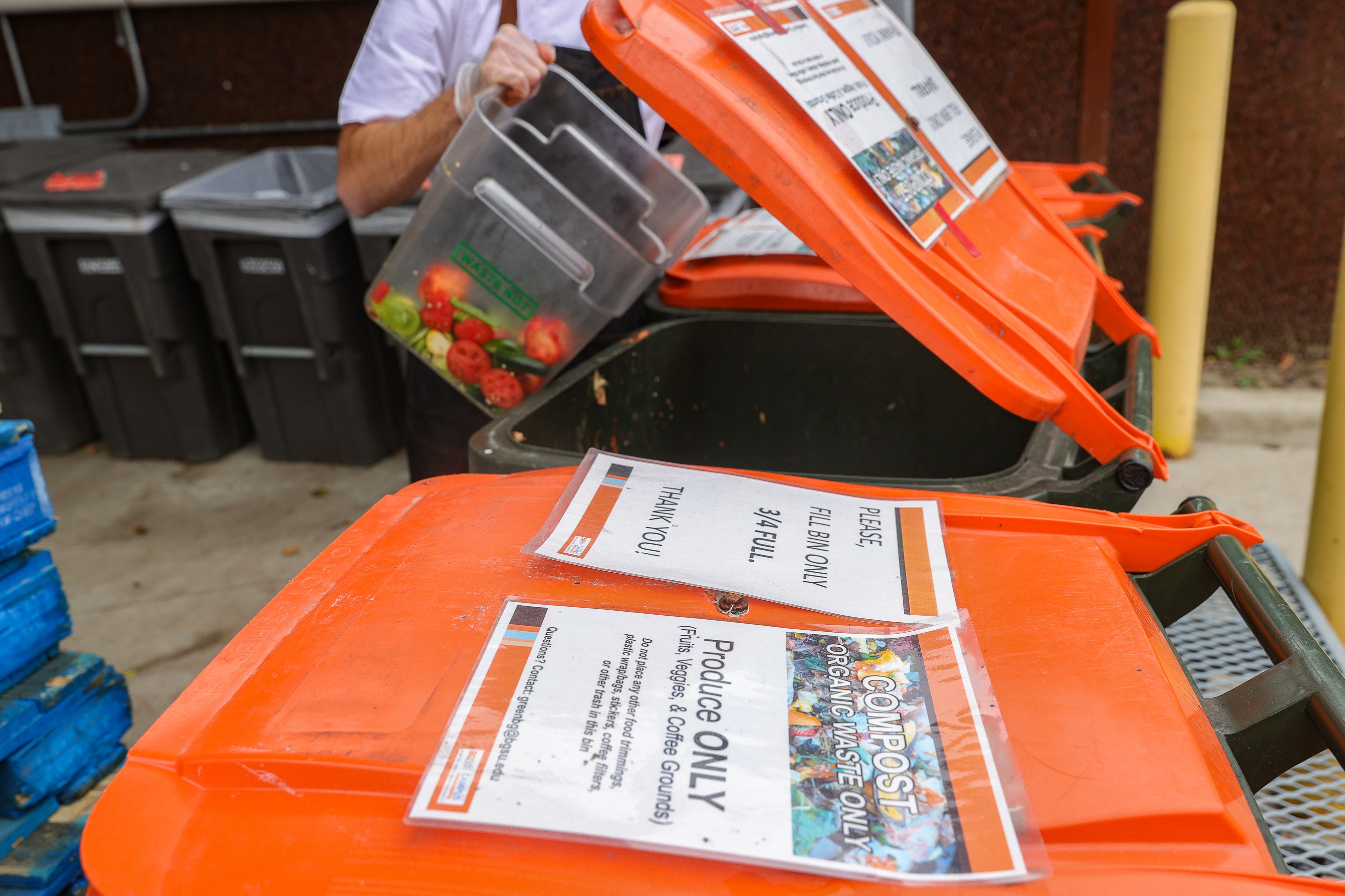 food waste being placed into bins with orange lids