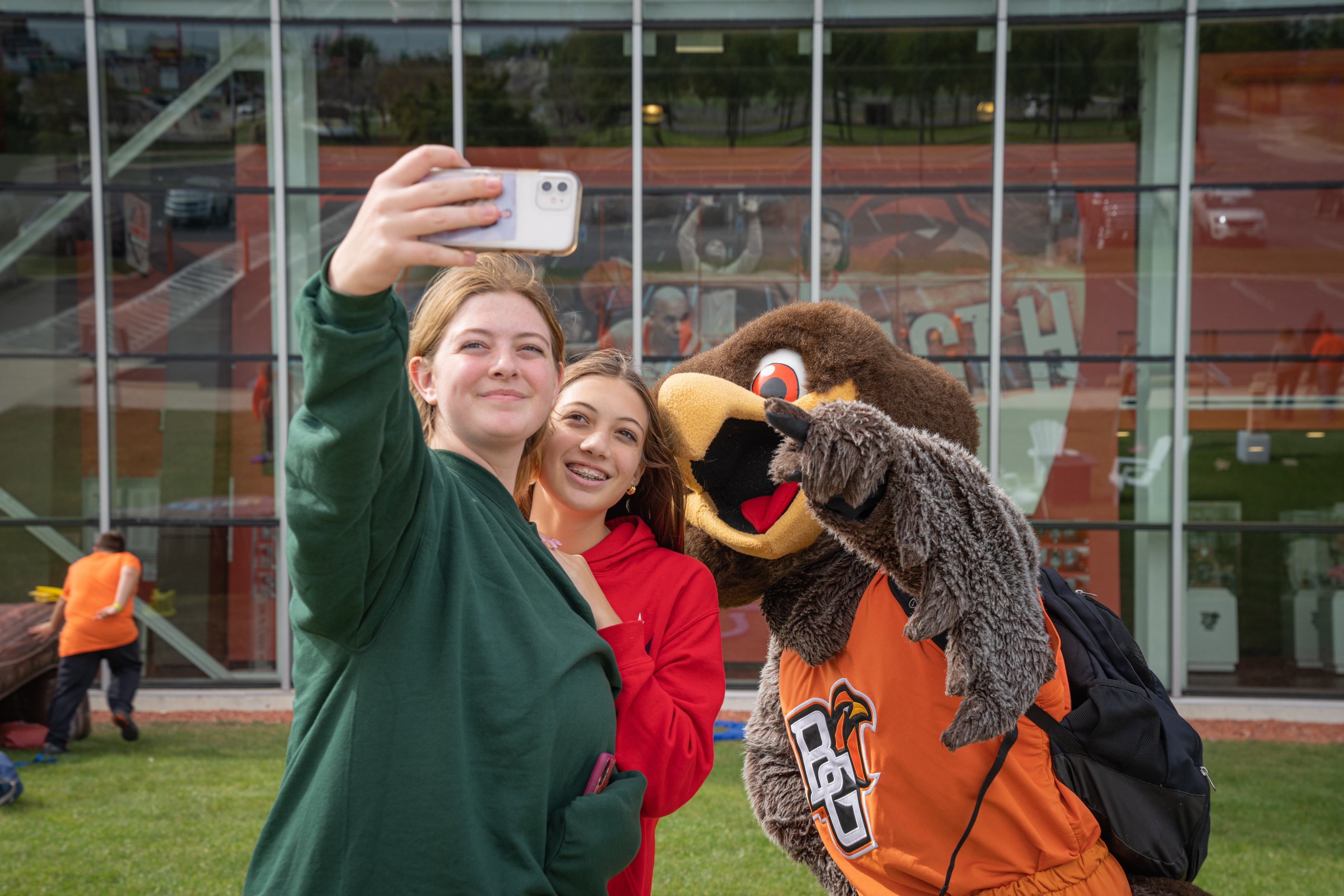 Two young ladies take a picture with a costumed mascot