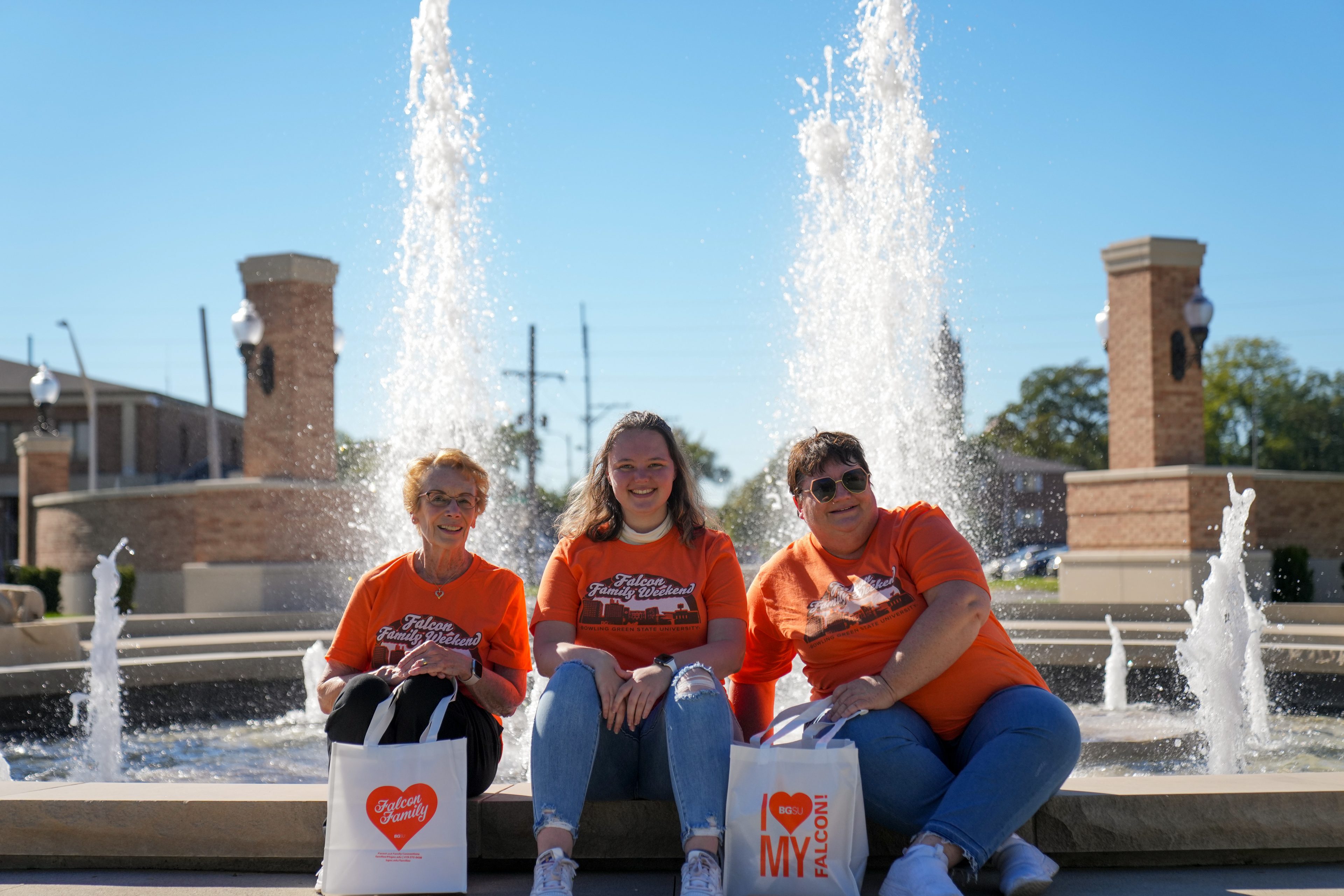 Three people sit near a fountain
