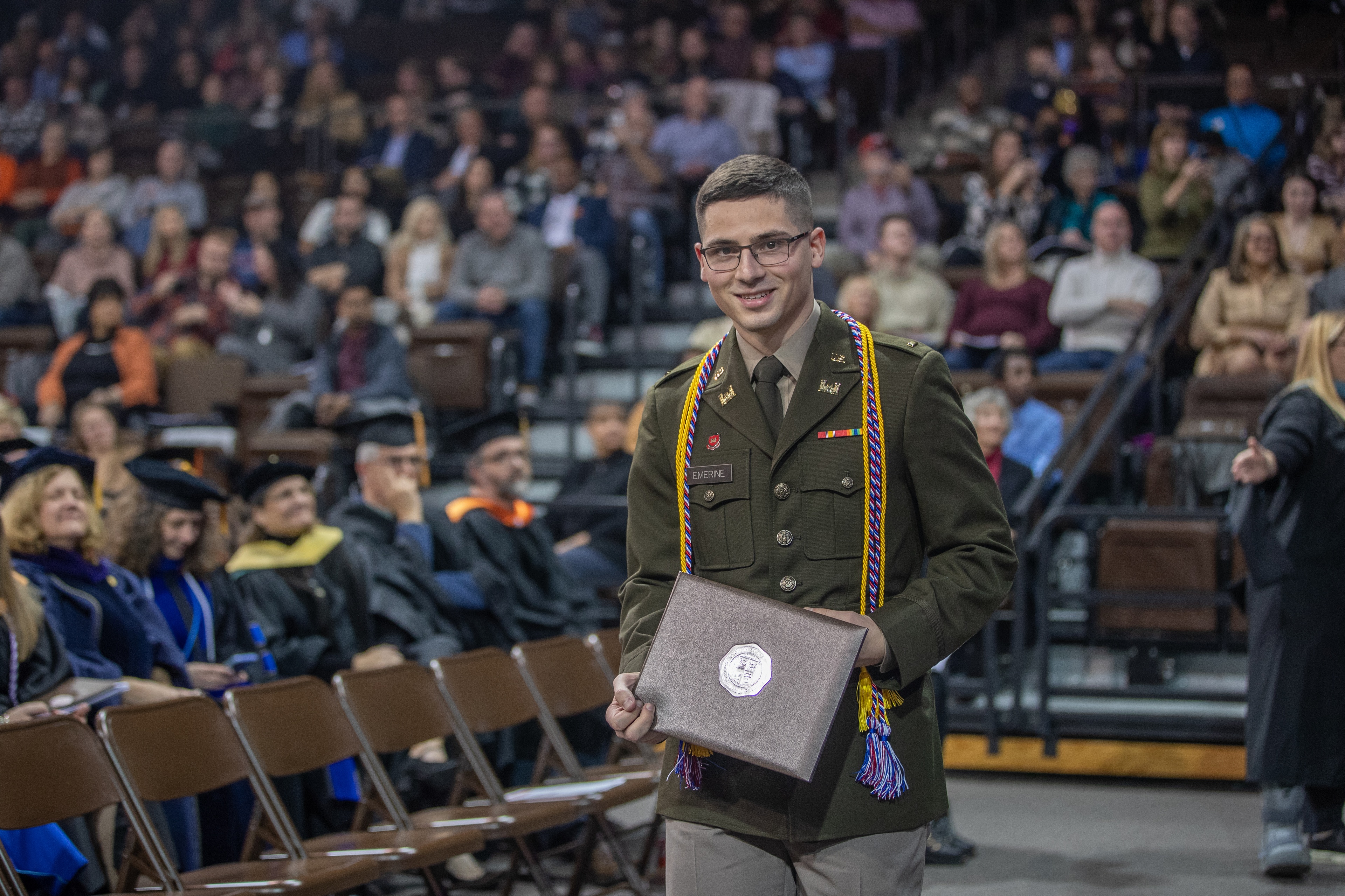 Student military member holds his diploma cover