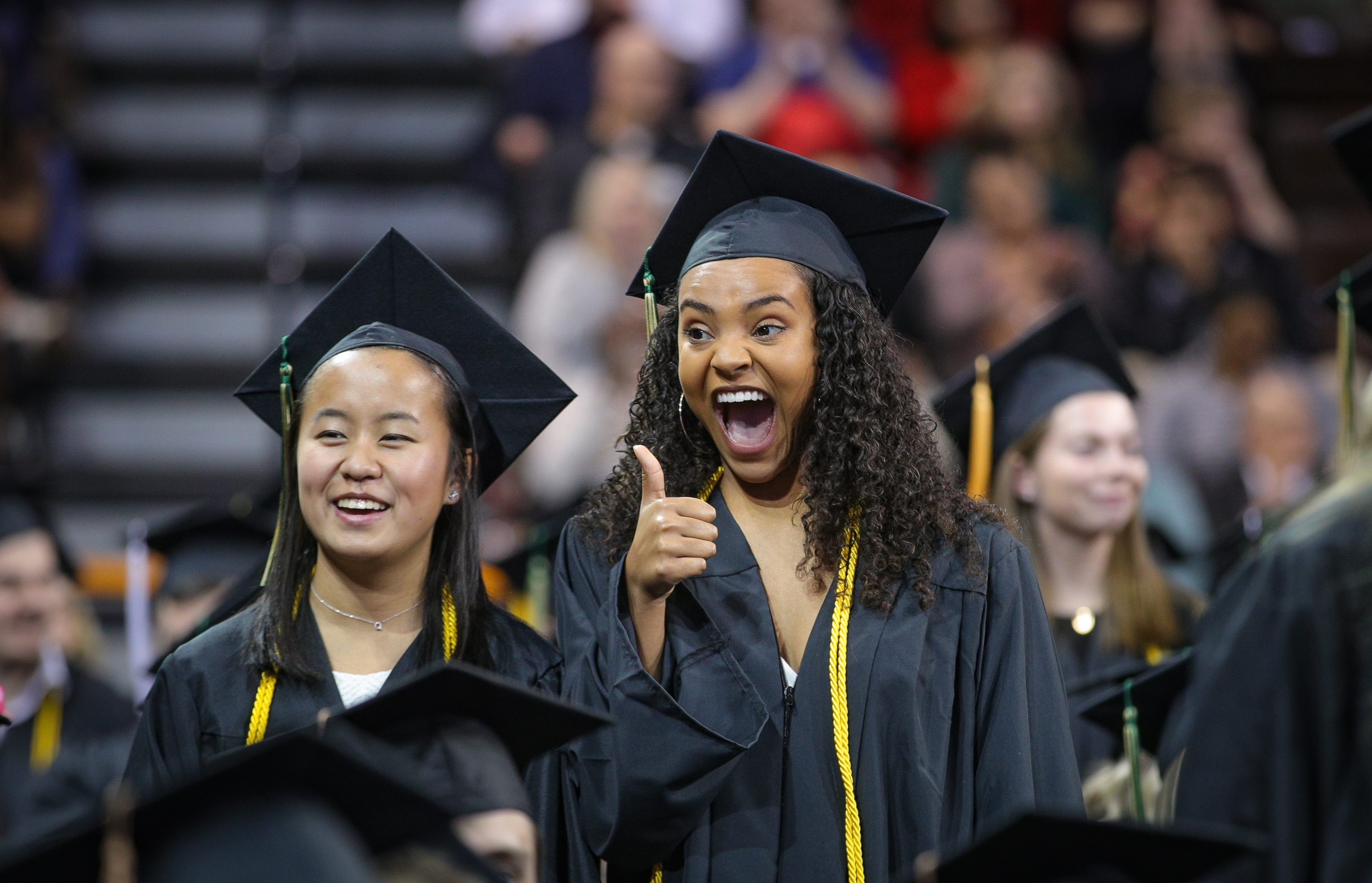 Female graduates smile and give a thumbs up