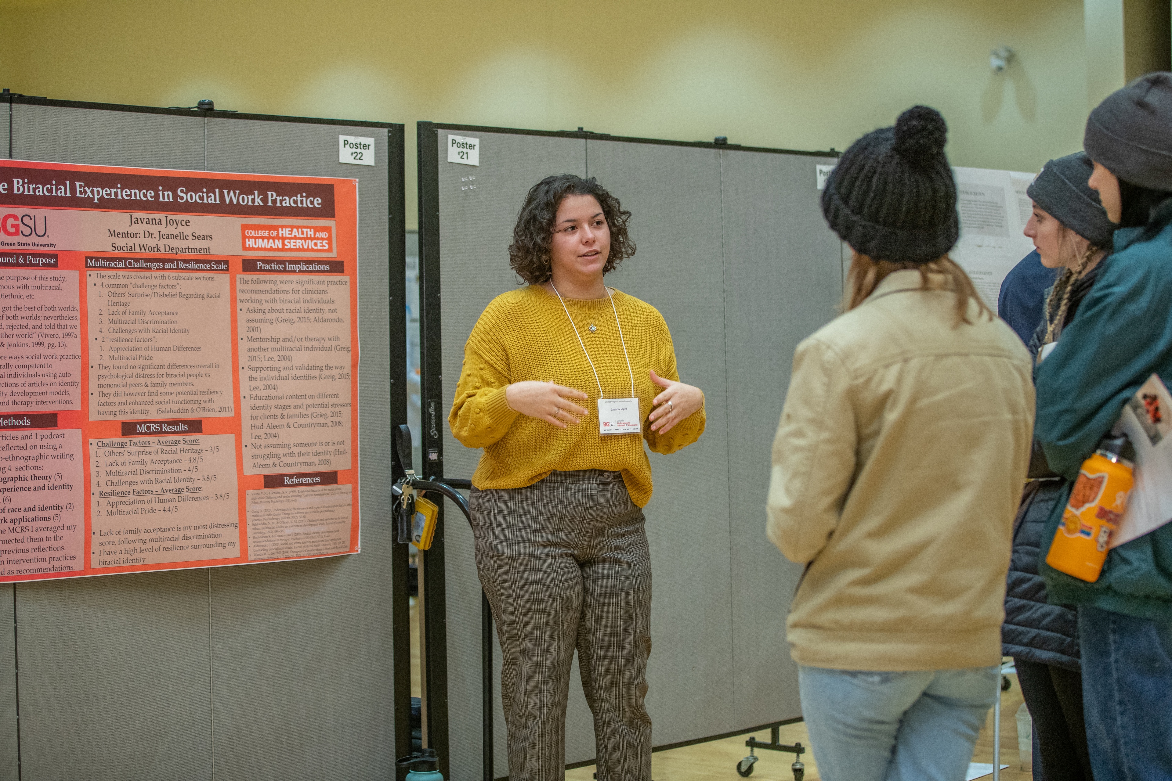 A student explains her poster to other students